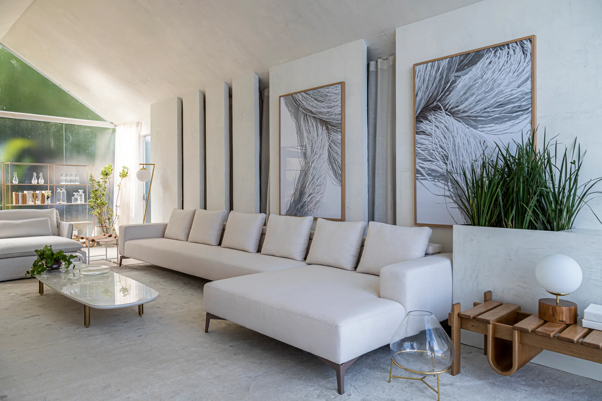 A large cream-colored sectional sofa sits in a minimalist living room with textured vertical wall paneling, framed abstract art, and a low coffee table.