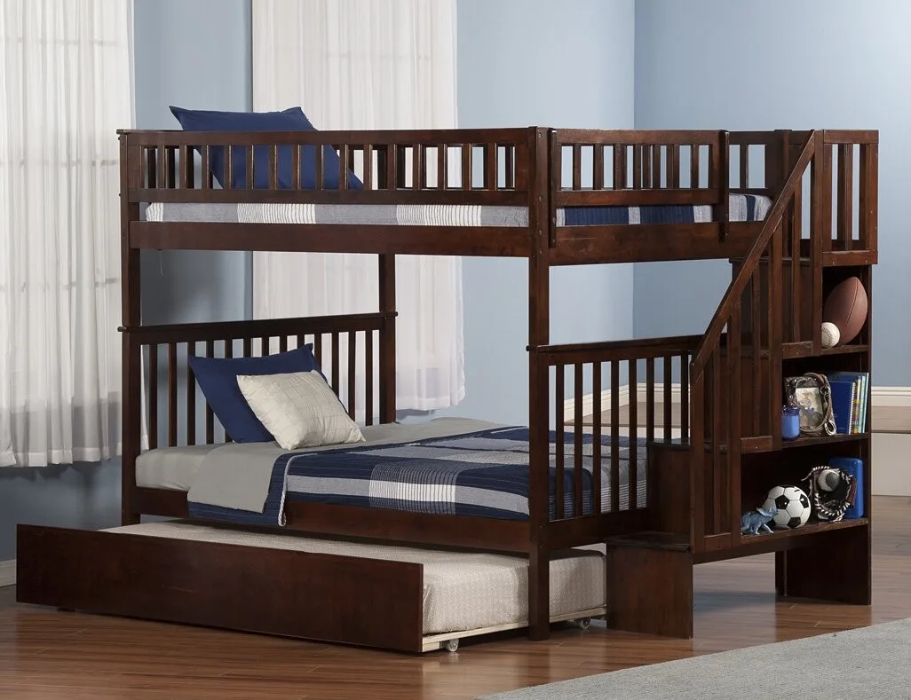 A dark brown wooden bunk bed featuring built-in stairs with open shelving on the side and a slide-out trundle bed on wood floors.