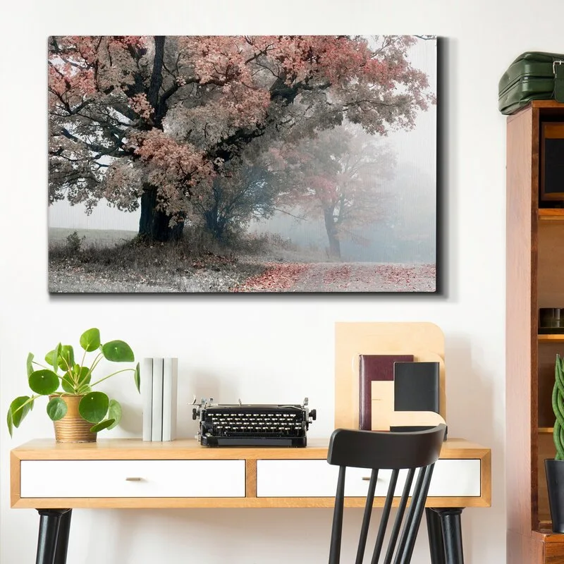 A mid-century modern wooden desk features a vintage black typewriter and a potted plant beneath a large landscape art print on a white wall.