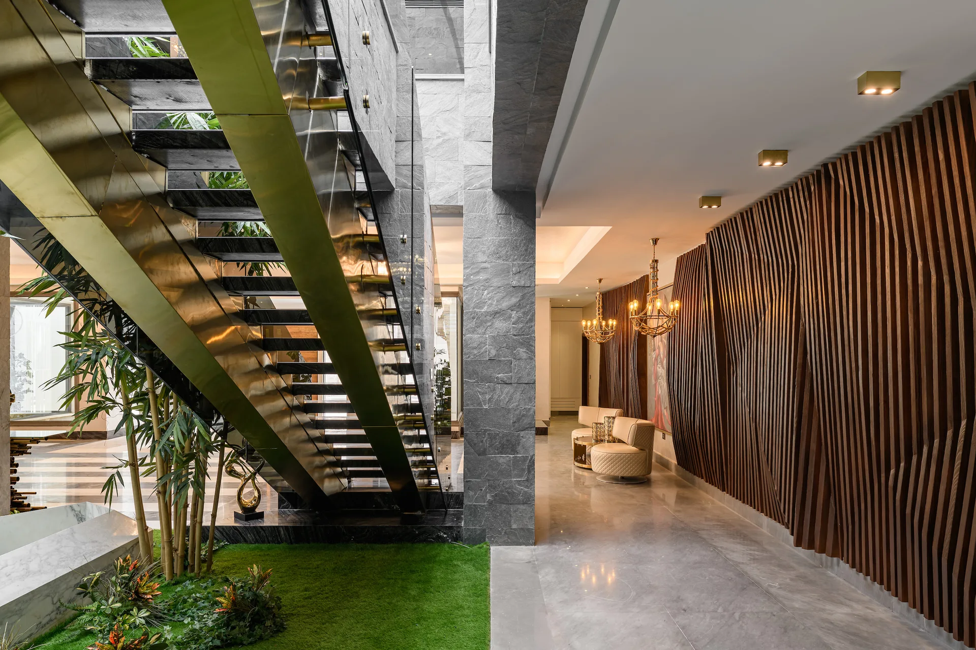 A modern hallway features a metallic staircase over an indoor garden, set against a wave-patterned slatted wood wall.