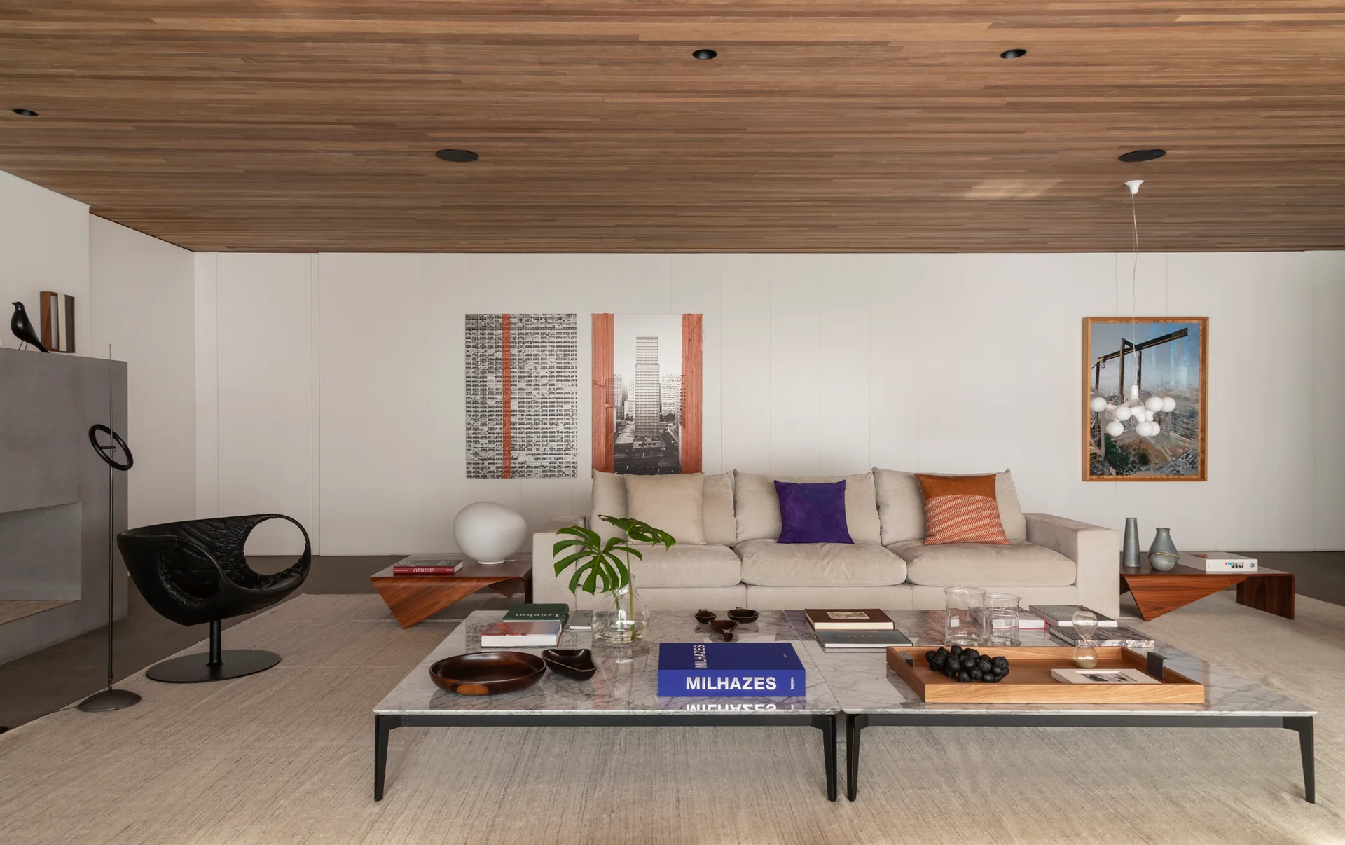 A contemporary living room featuring a cream sofa, double marble coffee tables, and a warm wood plank ceiling.