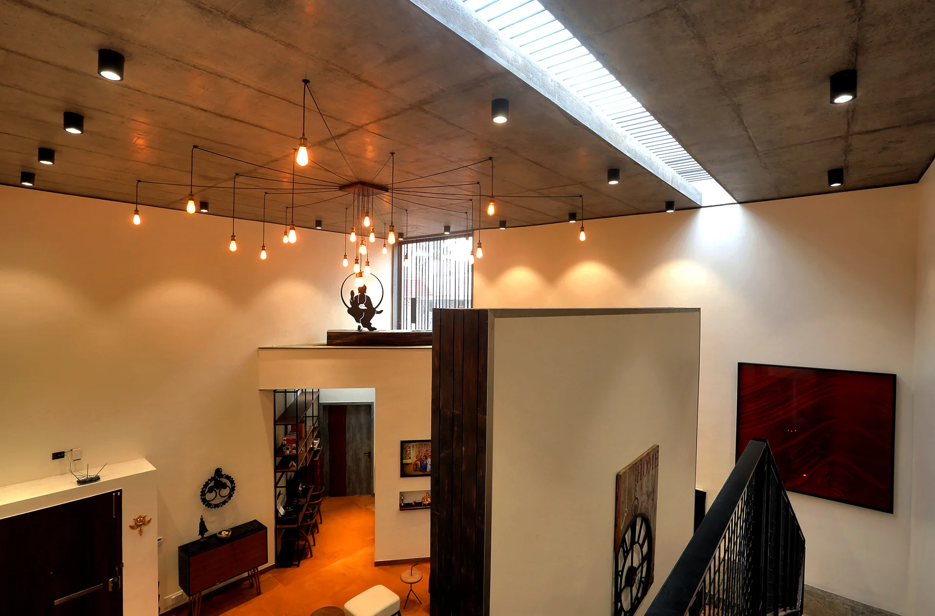 A modern multi-level home interior featuring a textured concrete ceiling with a long skylight, a spider chandelier, and a wood-clad partition wall.