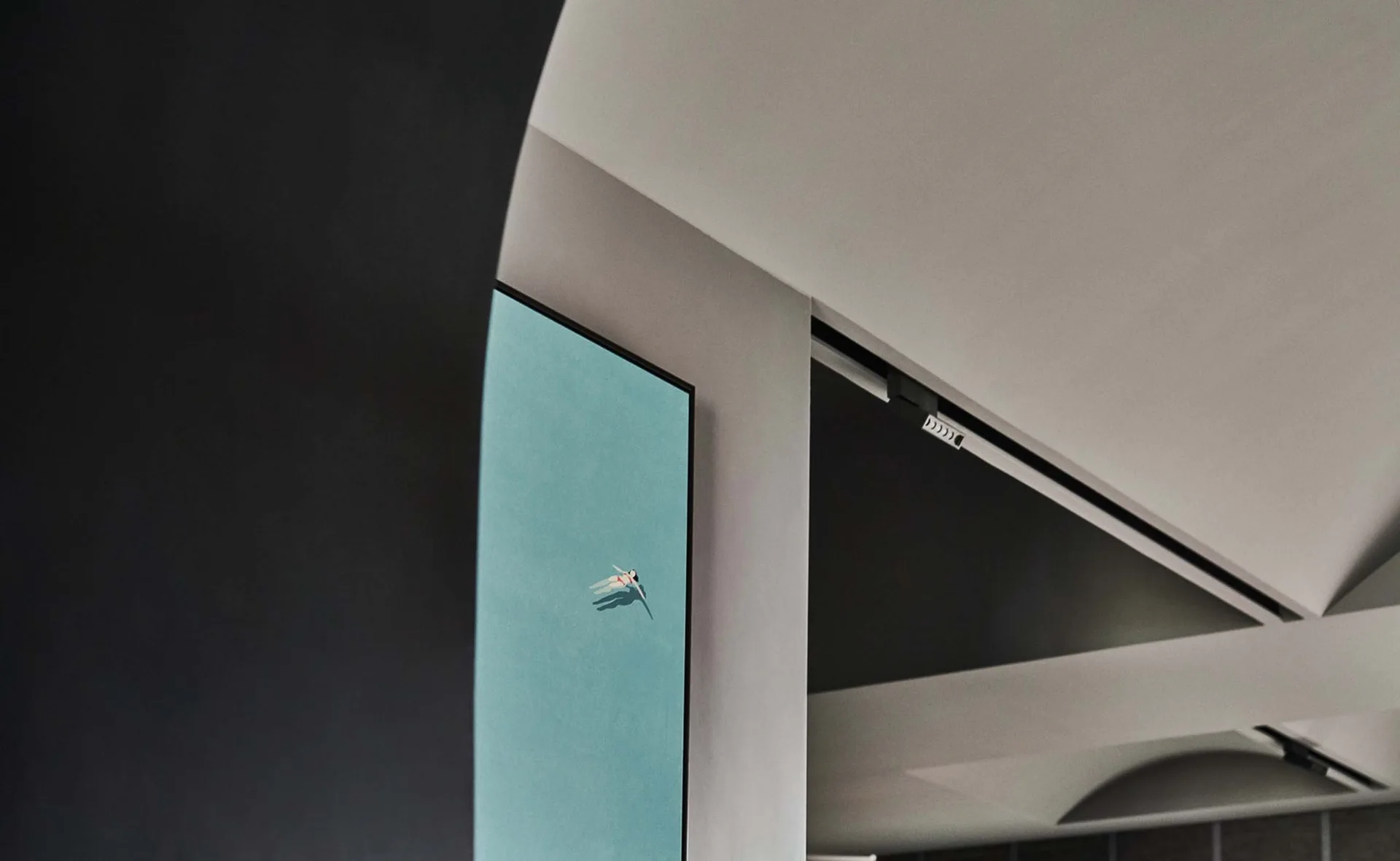 A minimalist interior view of structural white walls and geometric black beams featuring a framed teal painting of a lone swimmer.