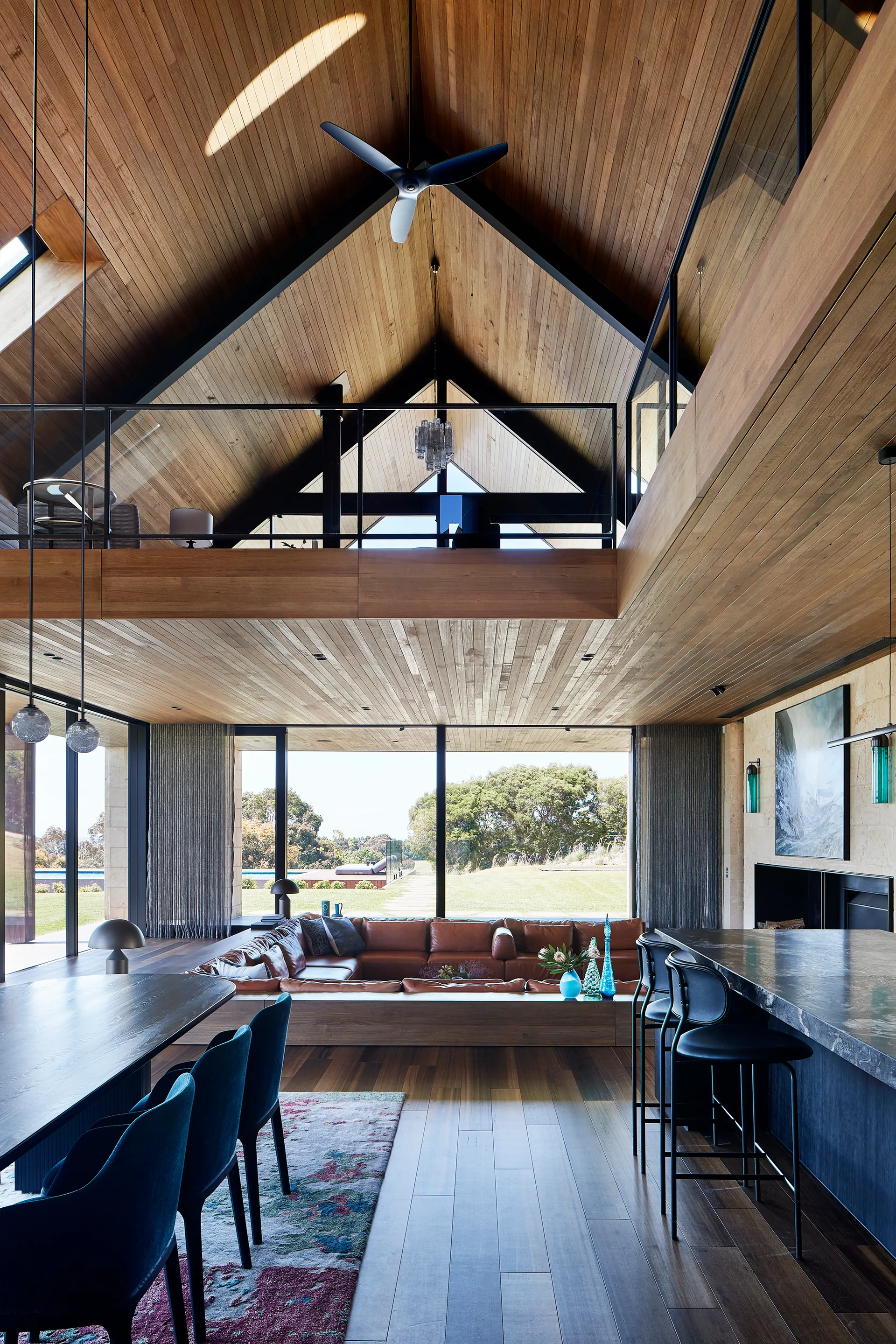 A spacious open-concept living area features a sunken leather conversation pit, vaulted wood-paneled ceilings, and a mezzanine balcony.