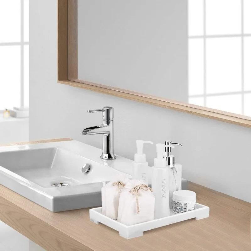 A bathroom vanity with a light wood countertop, a white vessel sink, a chrome faucet, and a small marble tray holding various toiletries.