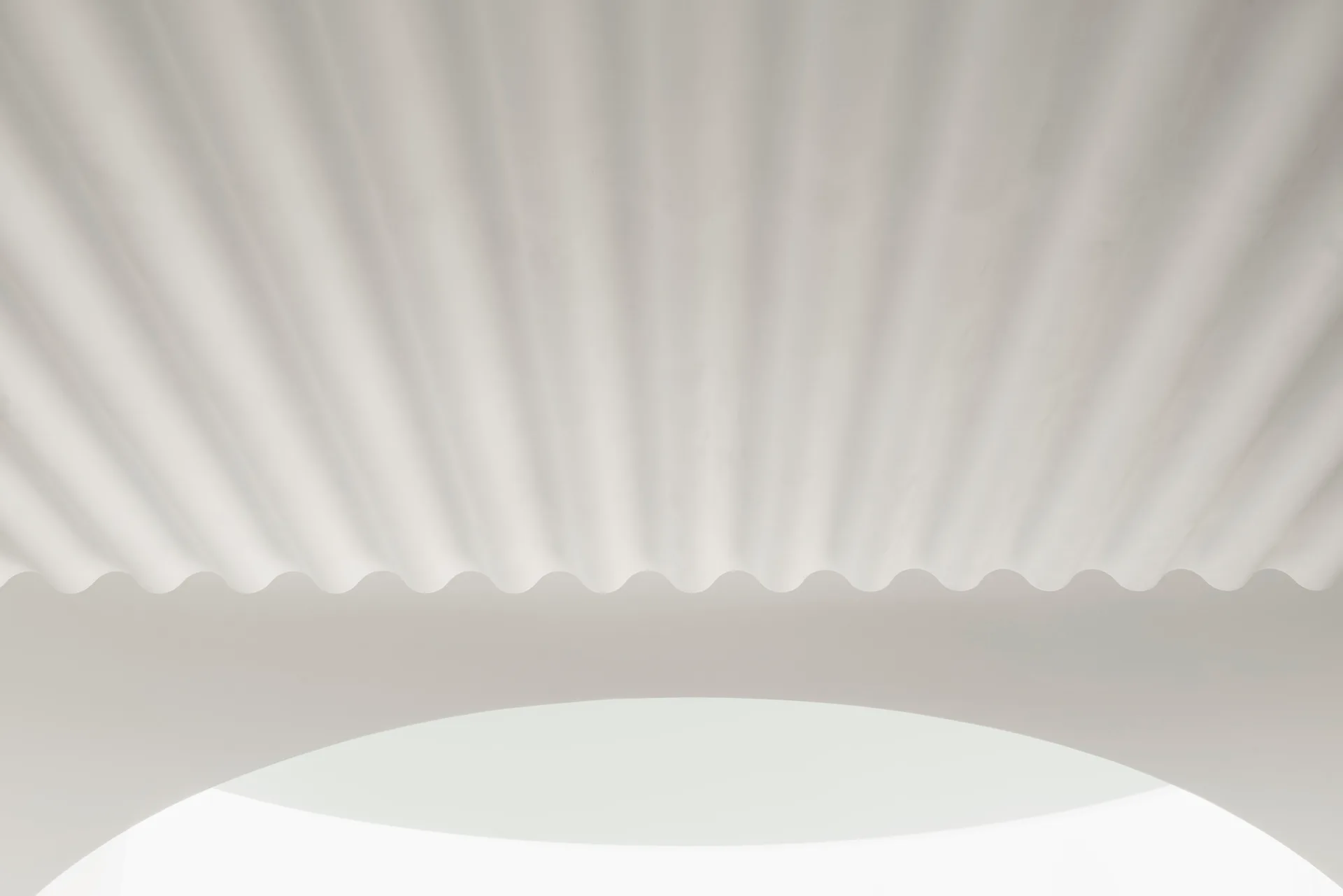 White plaster ceiling with a corrugated wave pattern positioned above a smooth, curved archway in a minimalist space.