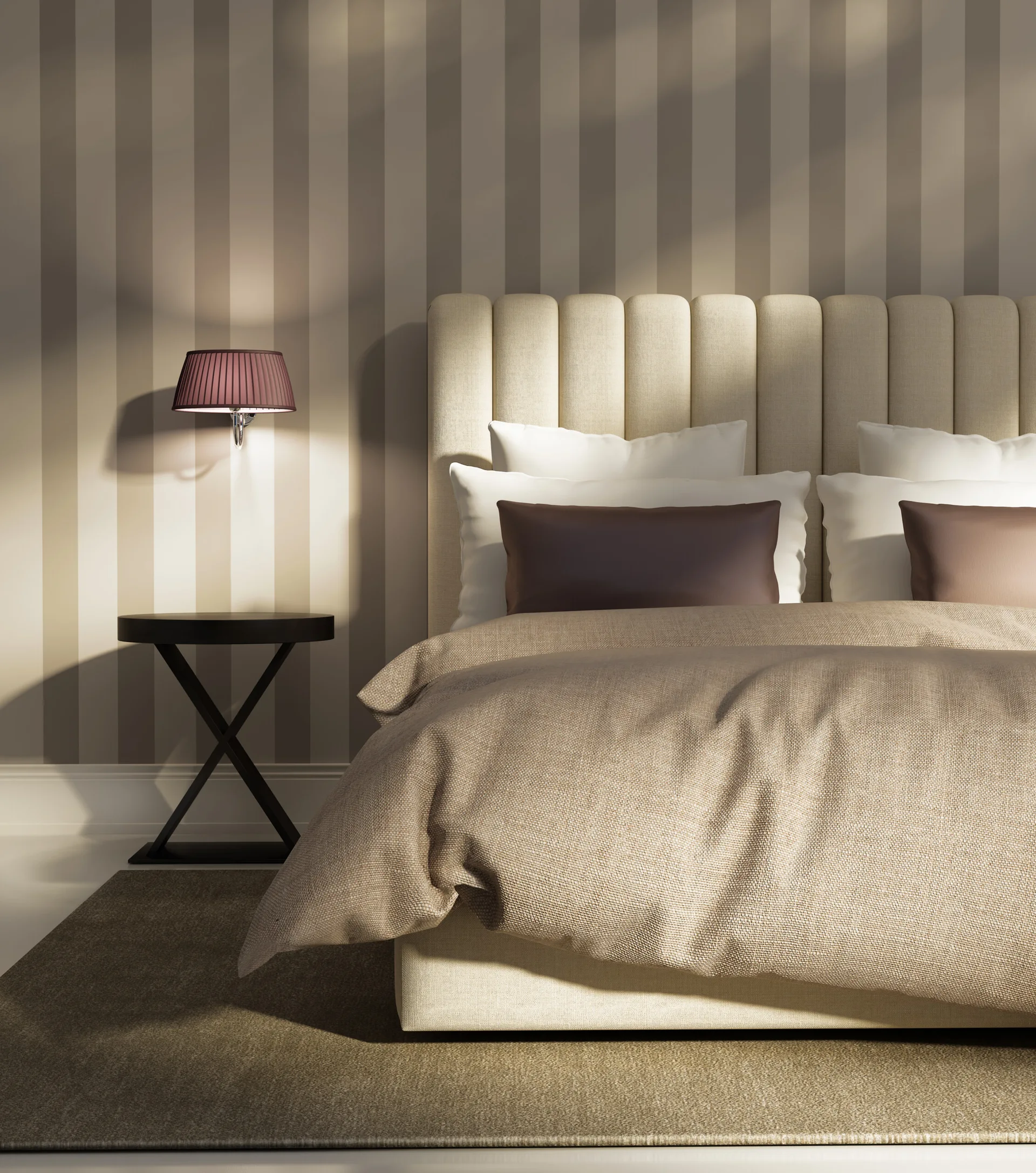 A neutral-toned bedroom features a channel-tufted cream headboard against vertically striped wallpaper, flanked by a black side table and wall sconce.
