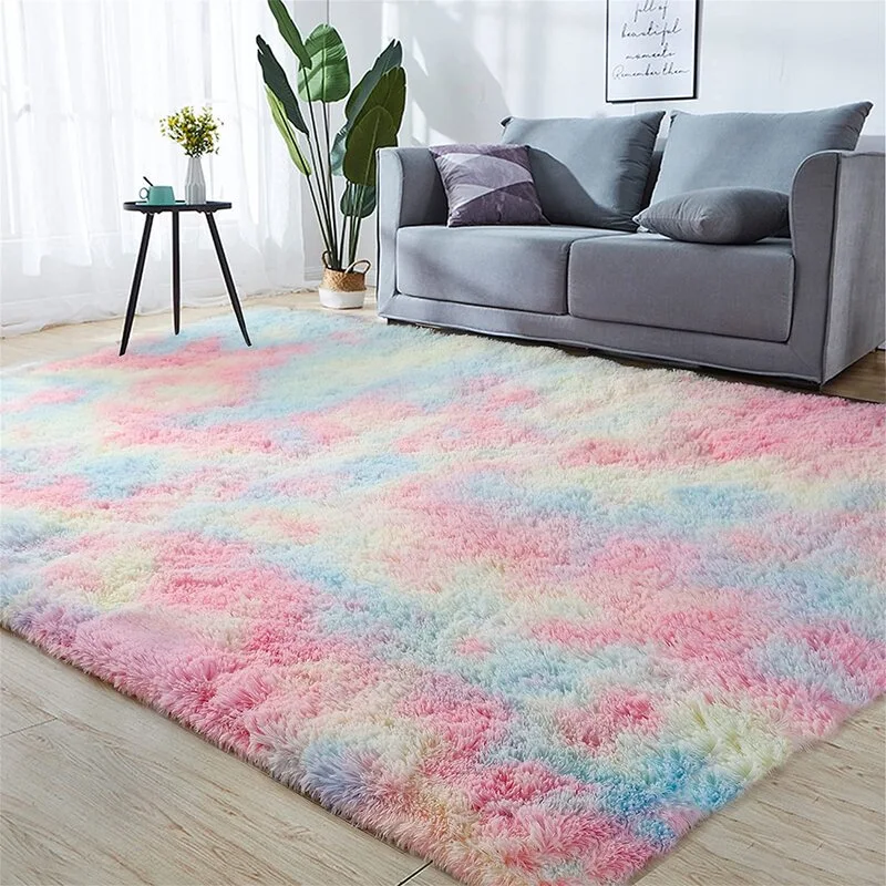 A large multicolored pastel shaggy rug sits on light wood flooring in front of a grey sofa and a small black side table.