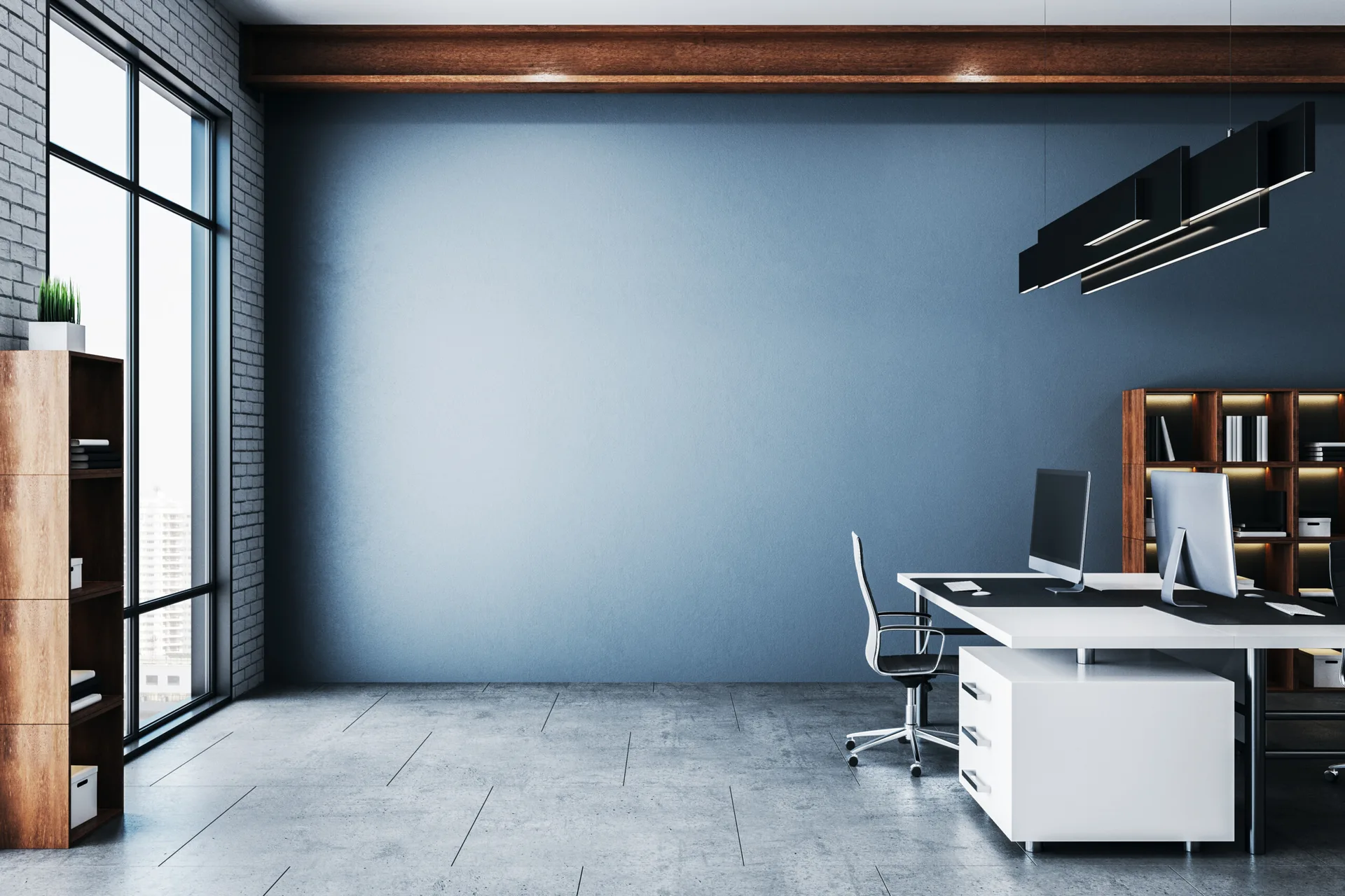 A modern minimalist office featuring a large blue feature wall, a white desk, a wood bookshelf, and an overhead wooden ceiling beam.