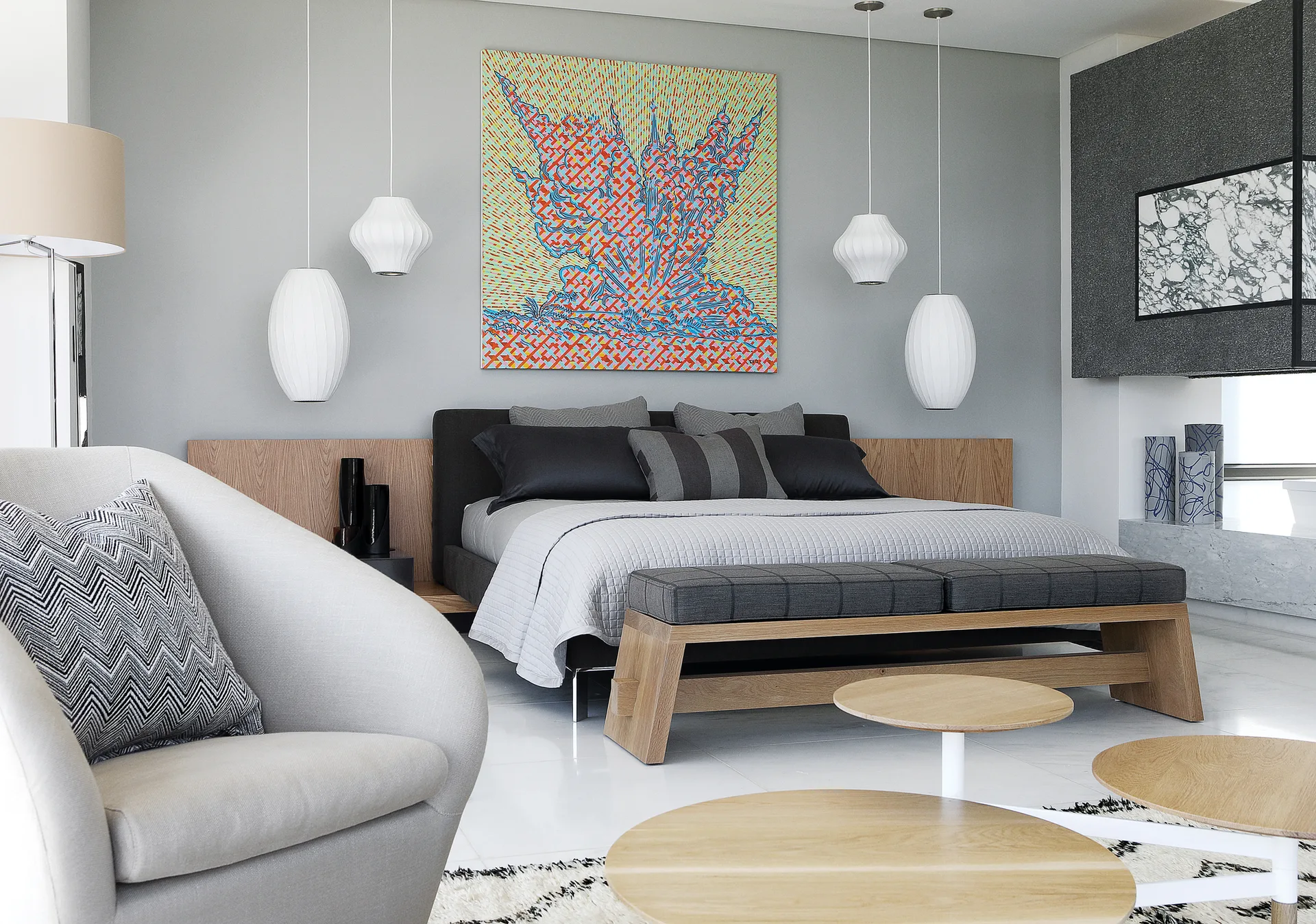 A modern bedroom features a low bed with grey bedding, a wood-paneled headboard wall, white ribbed pendant lights, and a vibrant abstract painting.