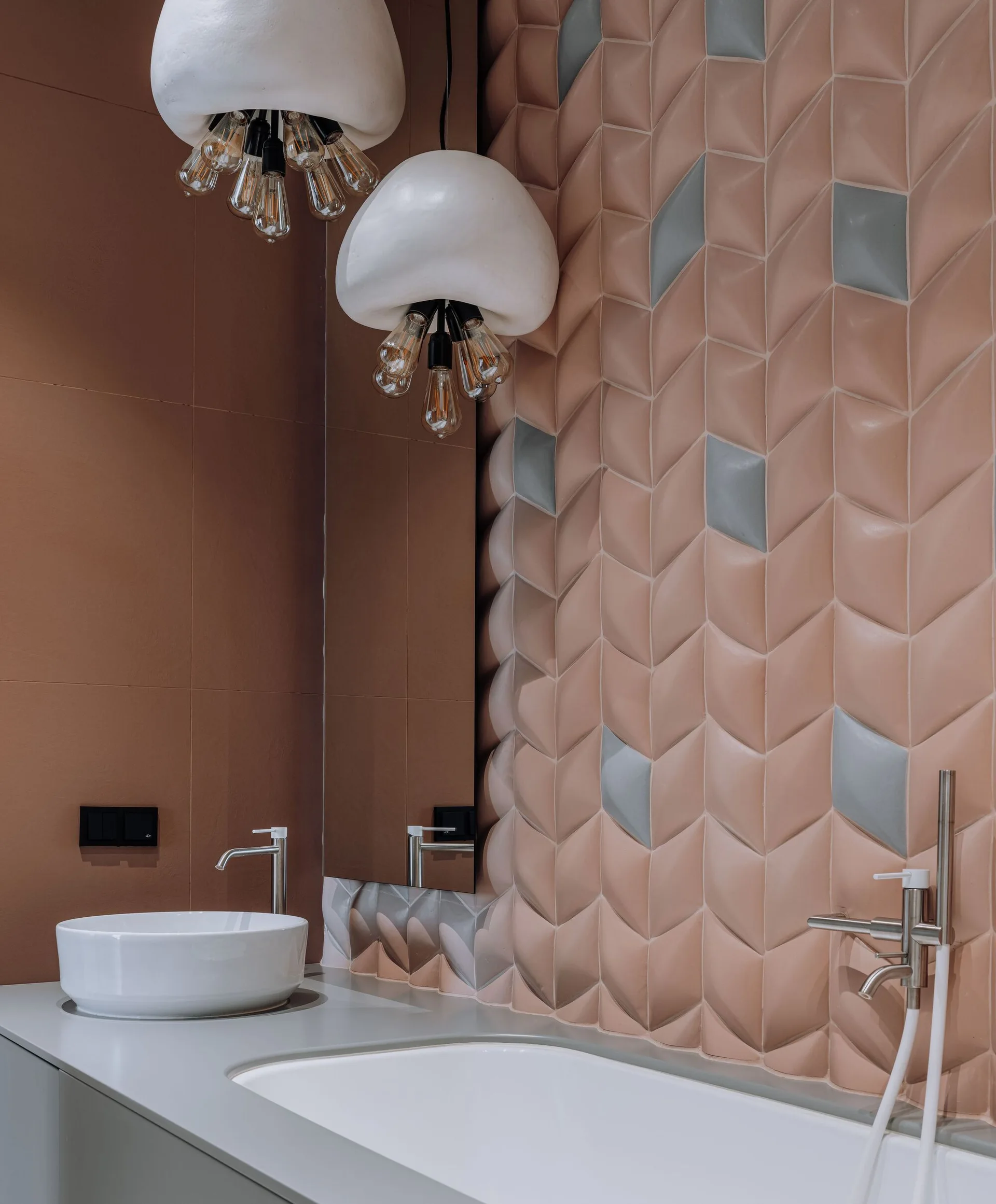 A modern bathroom vanity featuring textured pink geometric wall tiles, a white basin sink, and cloud-shaped pendant lights.