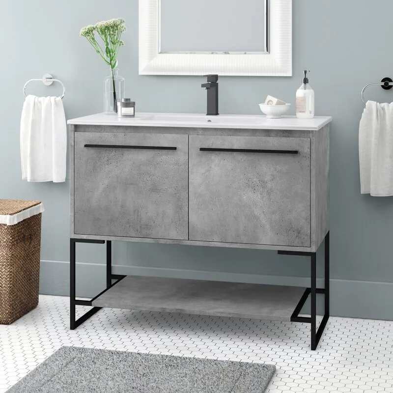 A grey concrete-finish bathroom vanity with black metal legs stands on a white hexagonal tile floor against a light blue wall.