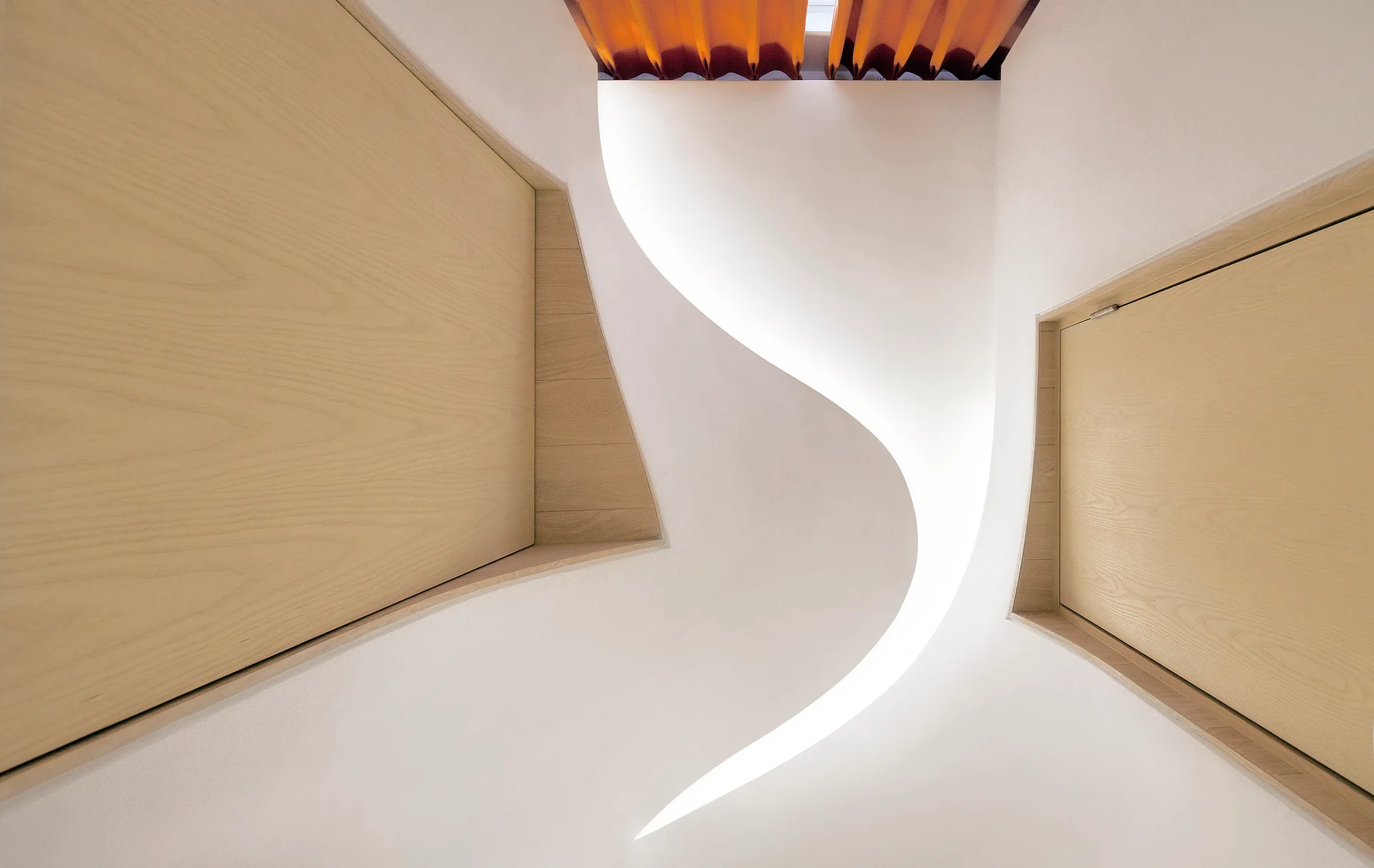 A low-angle view of a white sculptural staircase featuring a winding S-curve wall with integrated glowing light and recessed wood-paneled walls.