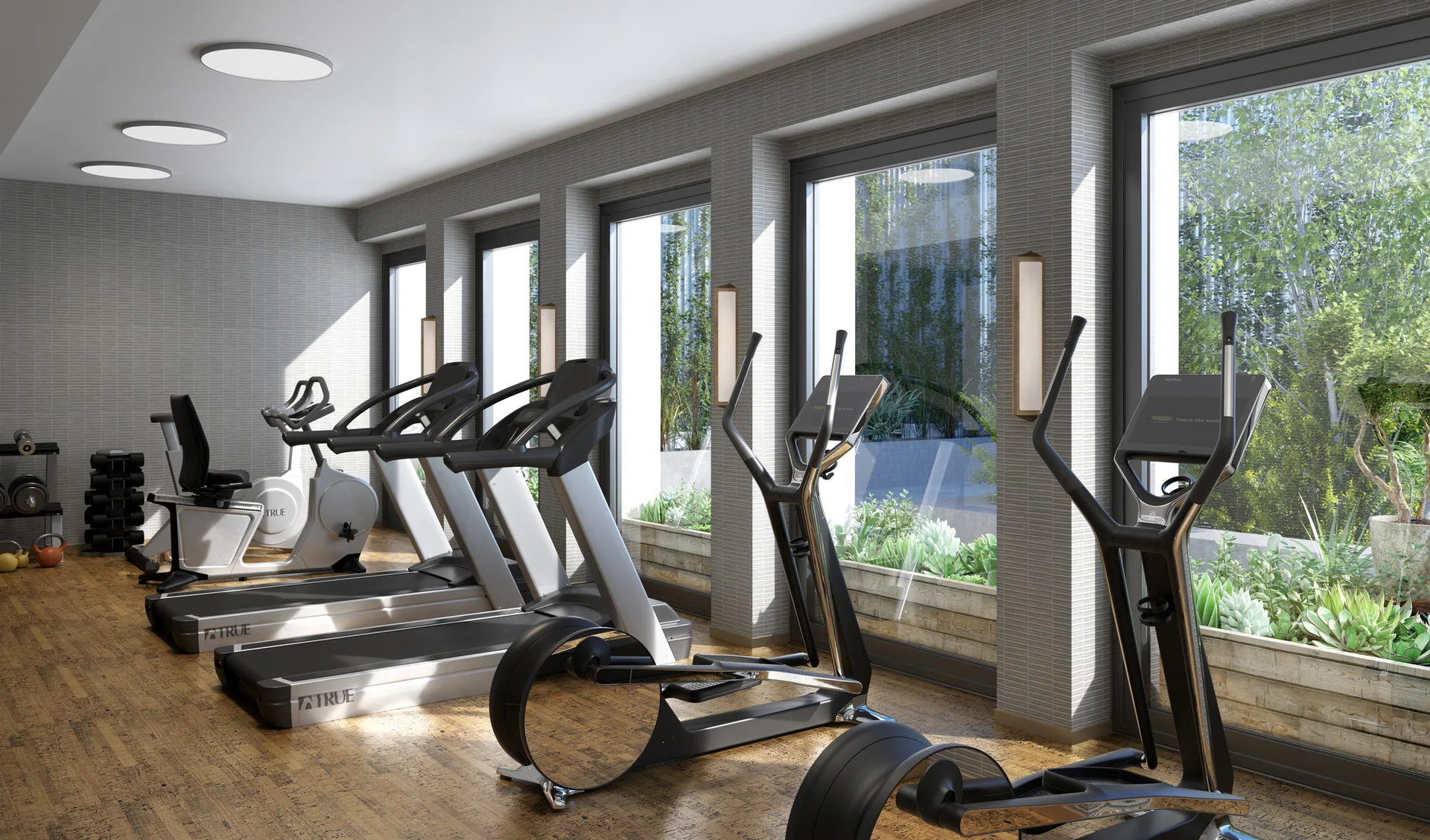 A modern home gym features a row of fitness equipment on wood floors next to large windows overlooking a landscaped terrace.