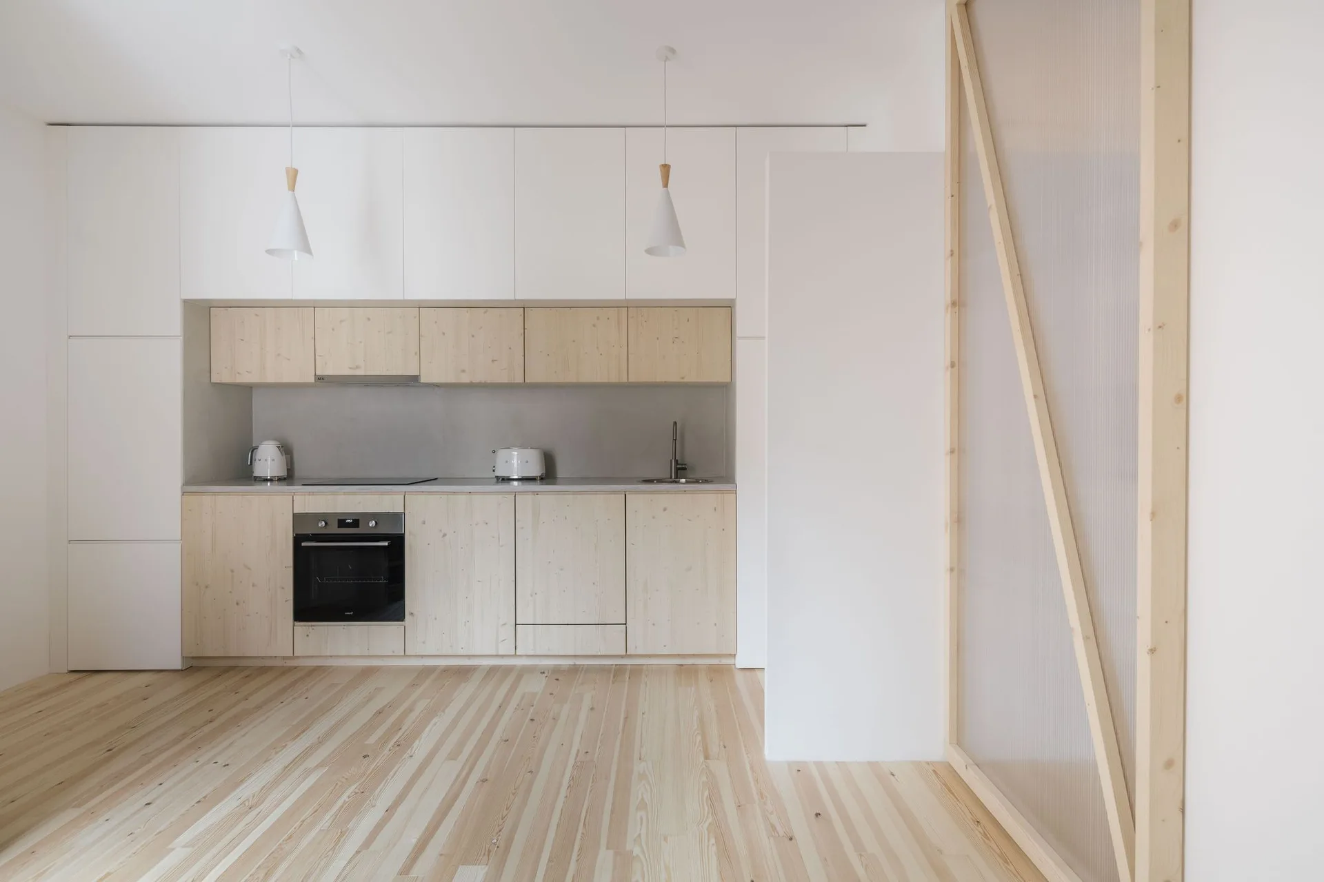 Minimalist kitchen featuring light wood cabinetry, white upper cupboards, a grey backsplash, and a wooden-framed translucent sliding screen.