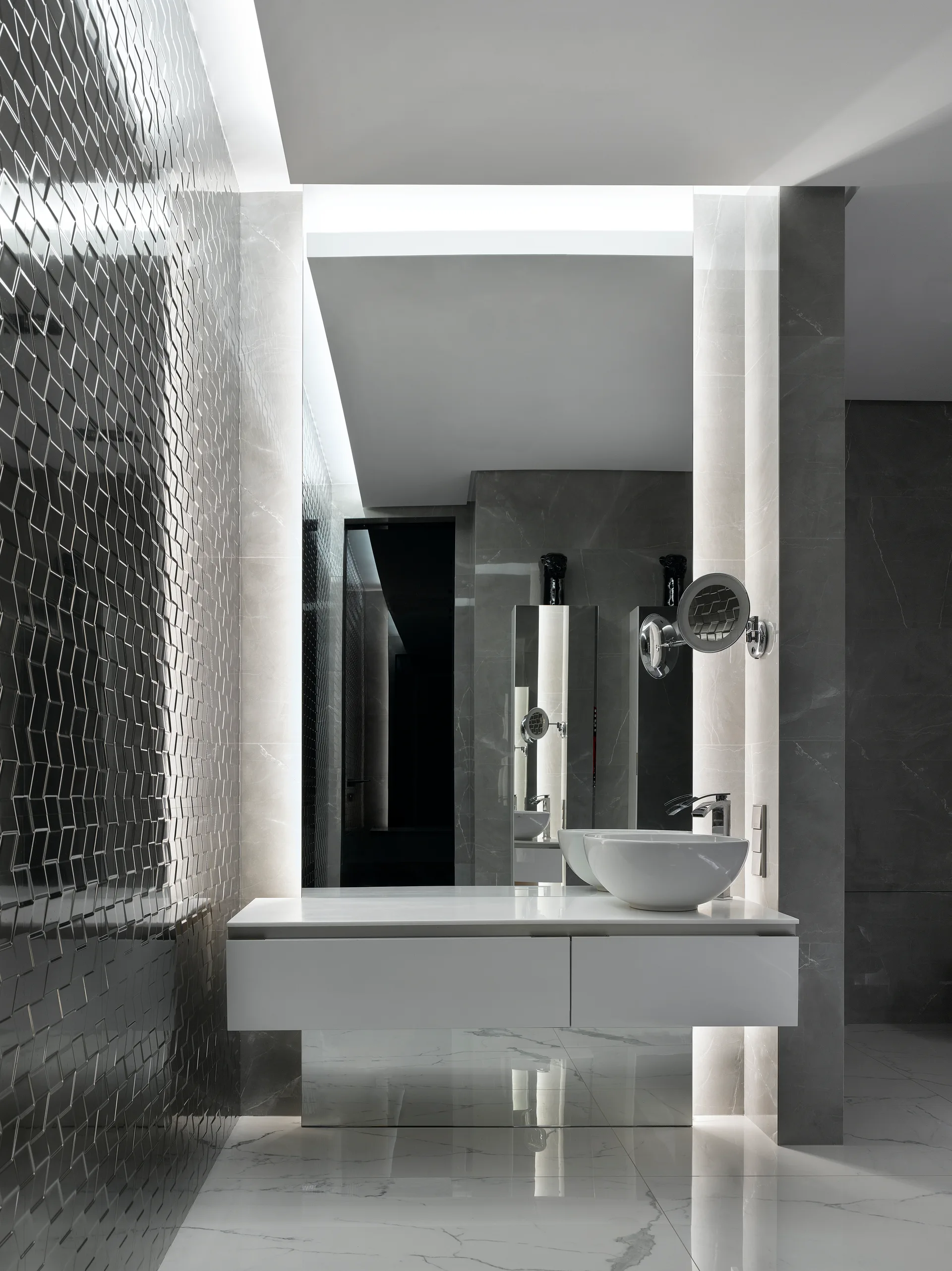 A modern bathroom featuring a white floating vanity with a vessel sink, set against a dark textured geometric tile wall and large marble panels.