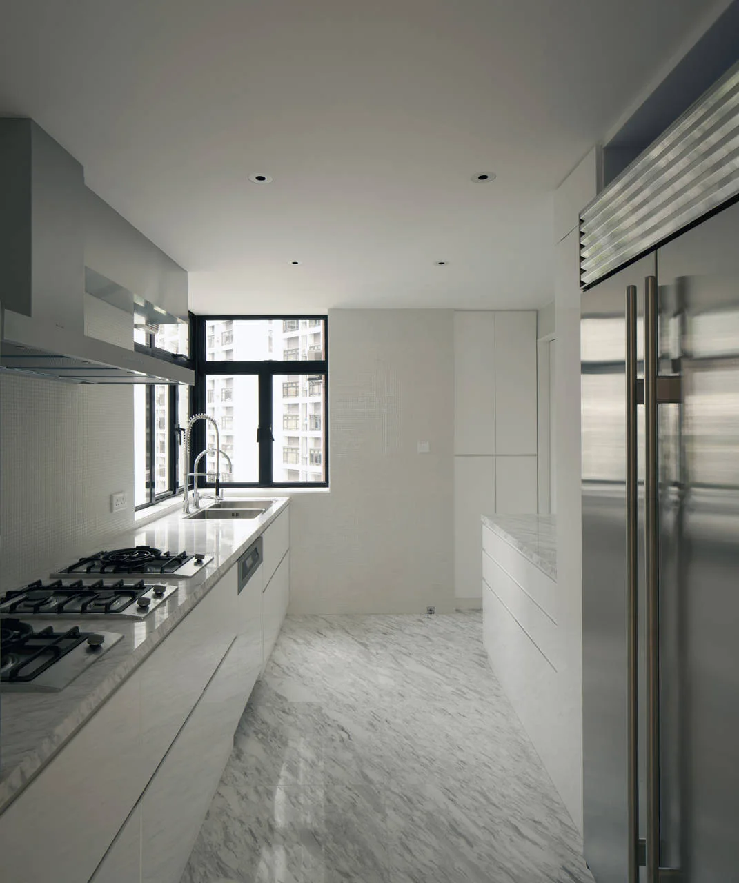 A modern galley kitchen features veined marble floors, white flat-panel cabinets, stainless steel appliances, and a black-framed window at the far end.