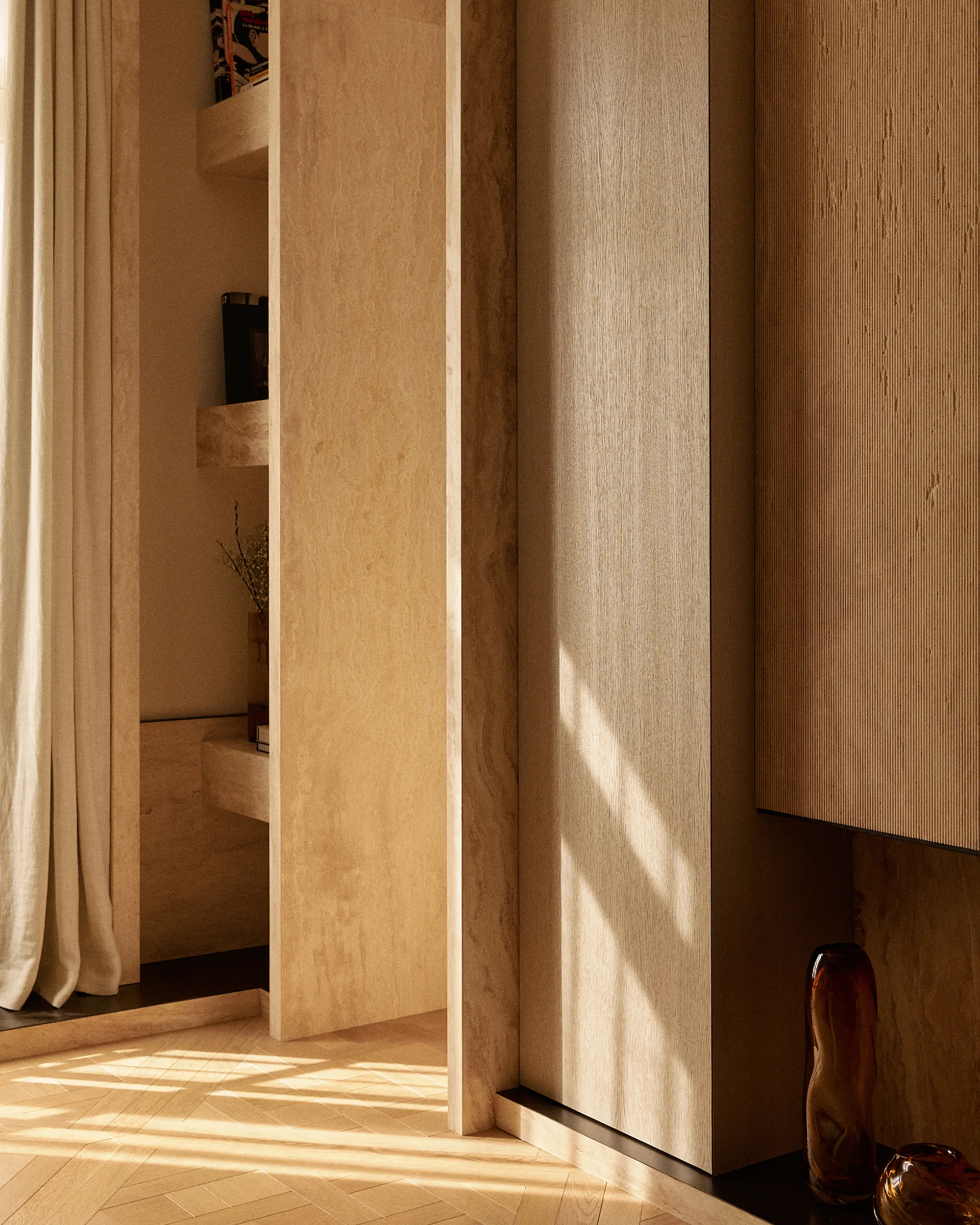 Built-in wooden cabinetry featuring fluted closet doors and recessed shelving stands on a herringbone parquet wood floor under bright sunlight.