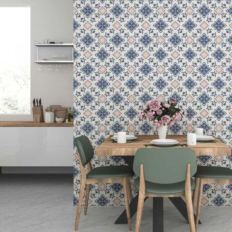 A dining space features a wooden table and sage green chairs set against a detailed blue and pink patterned wallpaper wall.