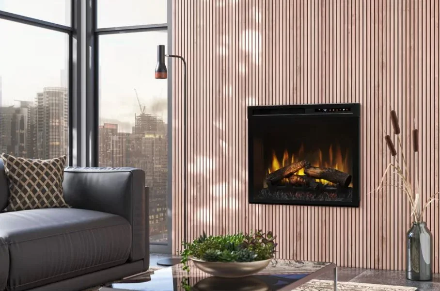 A modern living room features a wall-mounted electric fireplace on a light brown wood-slatted wall next to a dark leather sofa and large window.