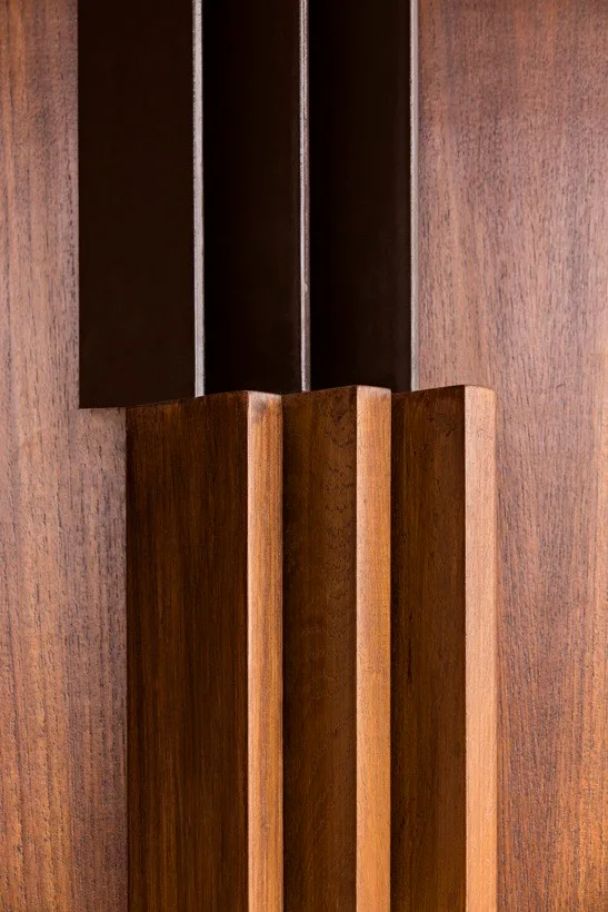 A close-up of textured vertical wood slats and recessed dark brown panels with a satin finish.