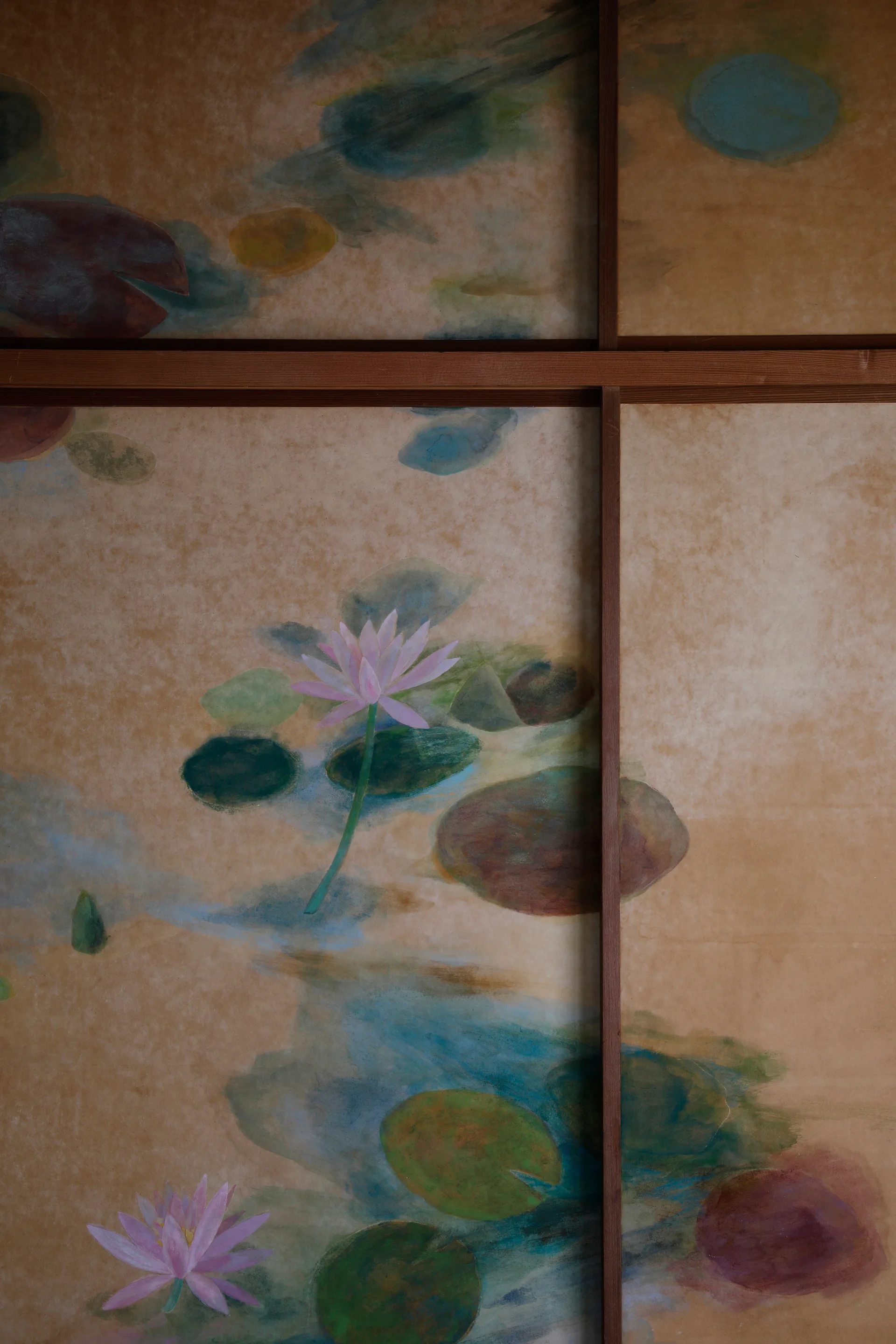 A Japanese sliding screen featuring a hand-painted watercolor mural of pink water lilies and green pads on textured tan paper with a wooden frame.