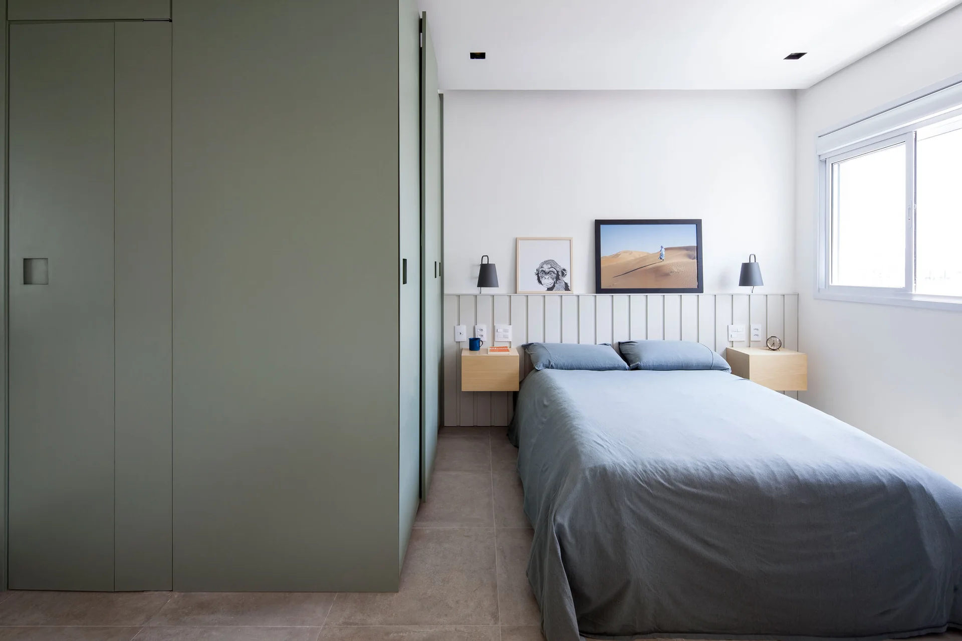 A modern bedroom features large sage green built-in cabinets next to a bed flanked by floating light wood nightstands and a vertical slat headboard.