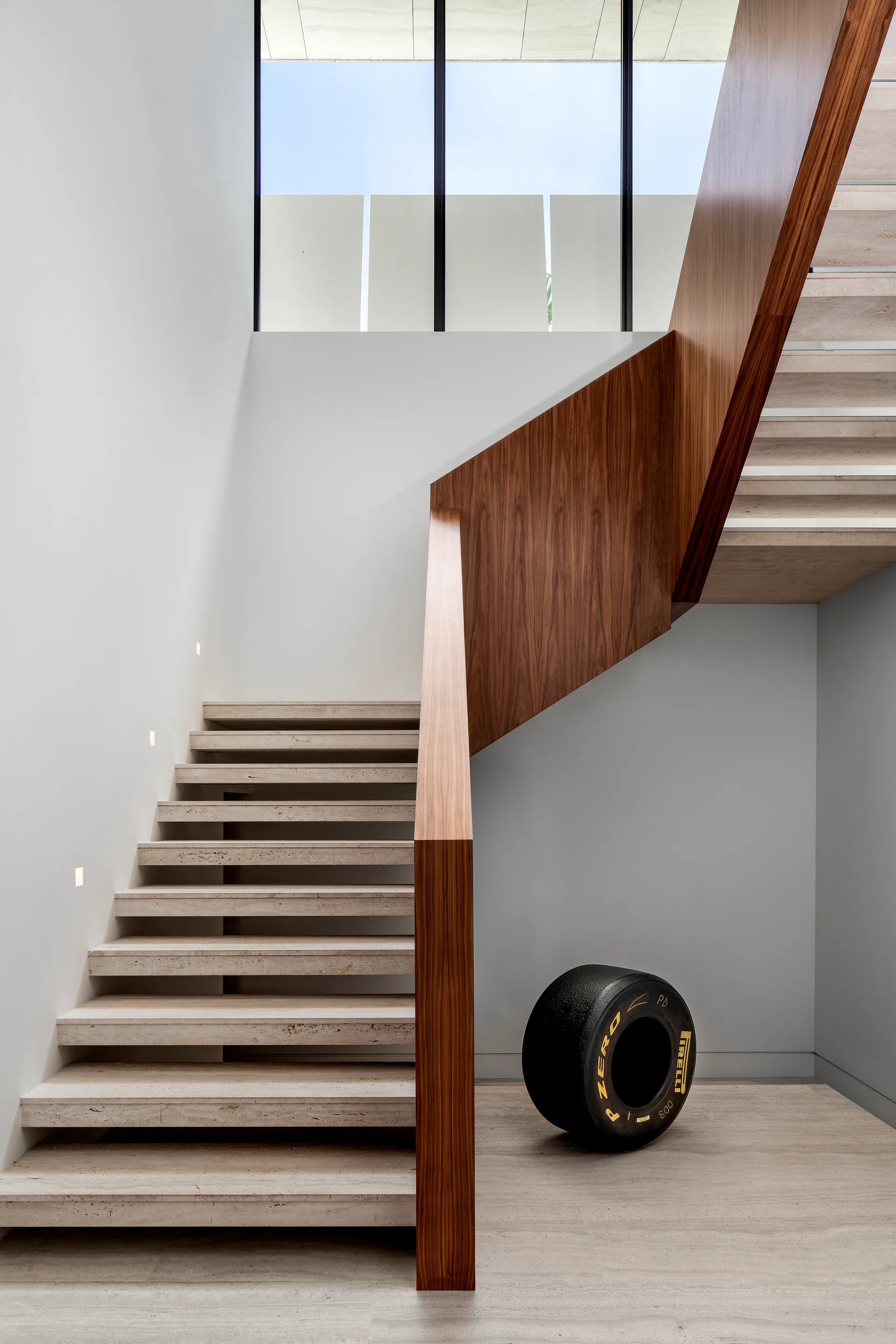 A minimalist modern staircase featuring floating stone treads, a solid wood guardrail, and low recessed wall lighting.