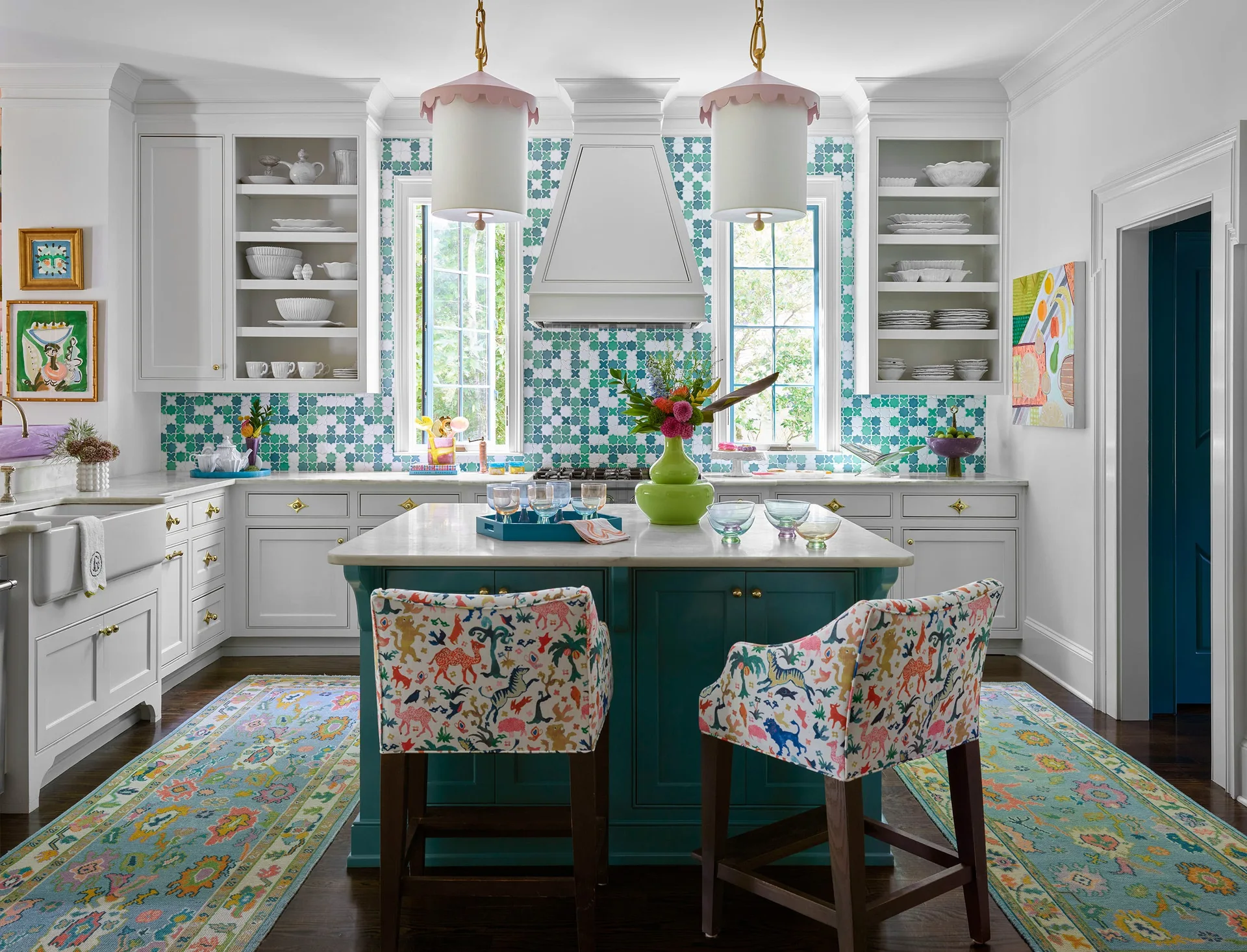 A colorful kitchen features a teal island with patterned stools, white cabinets, and a bright green and turquoise geometric tiled backsplash.