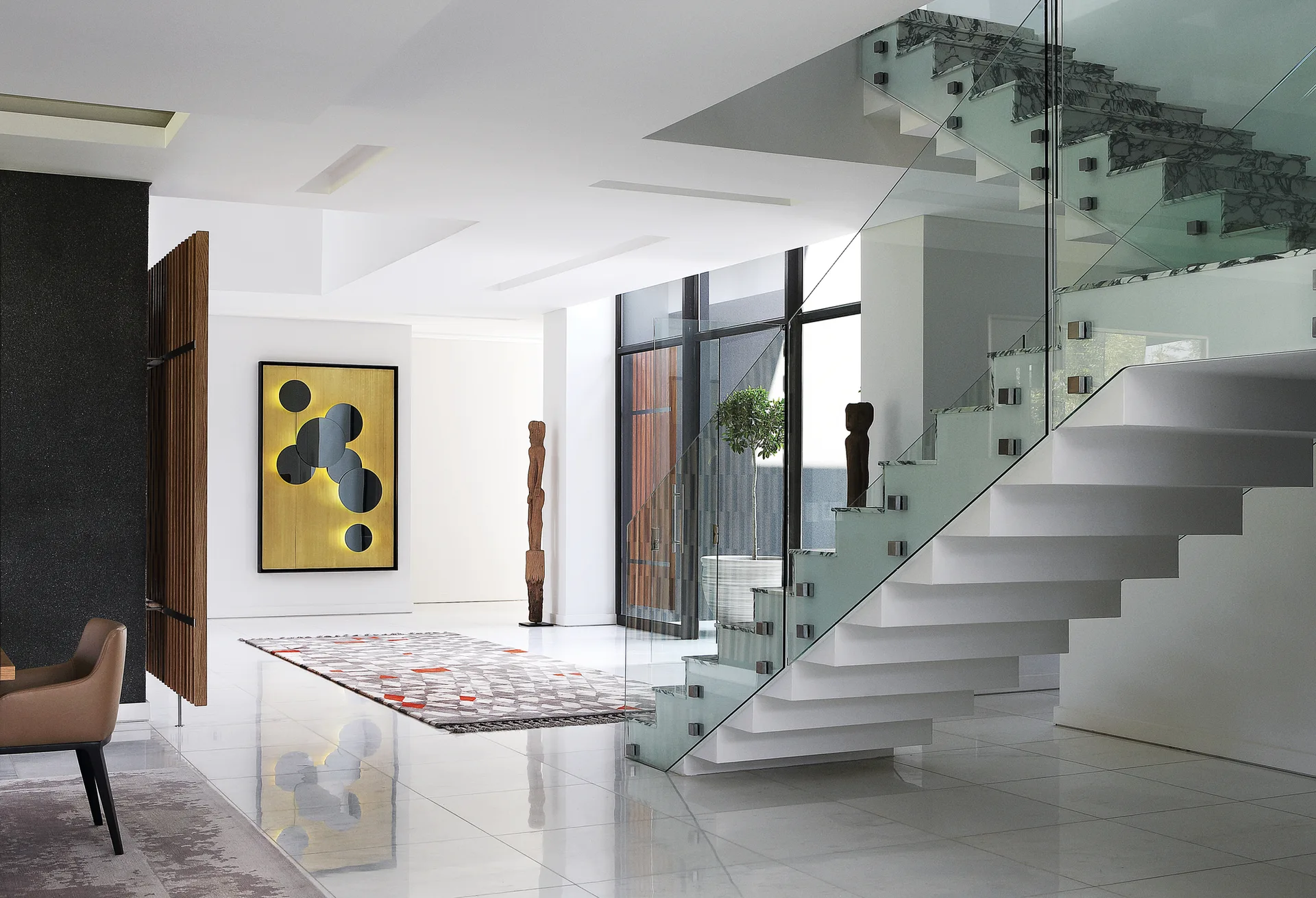 A minimalist white foyer featuring a floating staircase with glass railings, polished floors, and a geometric gold and black art piece.