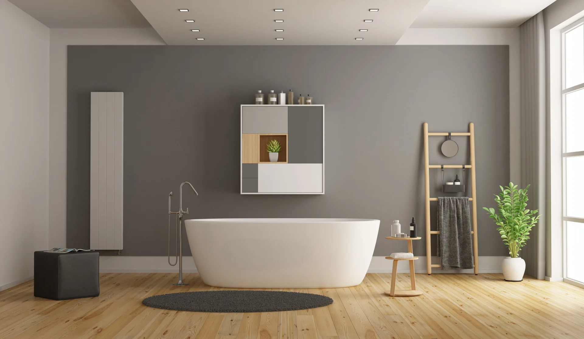 A minimalist bathroom featuring a white freestanding bathtub centered in front of a grey wall with a geometric cabinet and wooden ladder rack.
