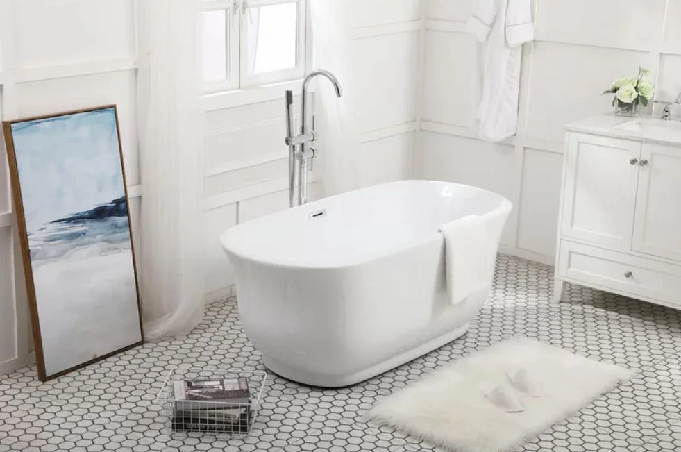 A bright white bathroom features a freestanding oval tub centered on small hexagonal floor tiles near a classic paneled wall.