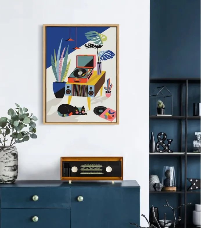 A deep blue sideboard sits below colorful framed graphic art on a white wall next to a dark blue alcove.