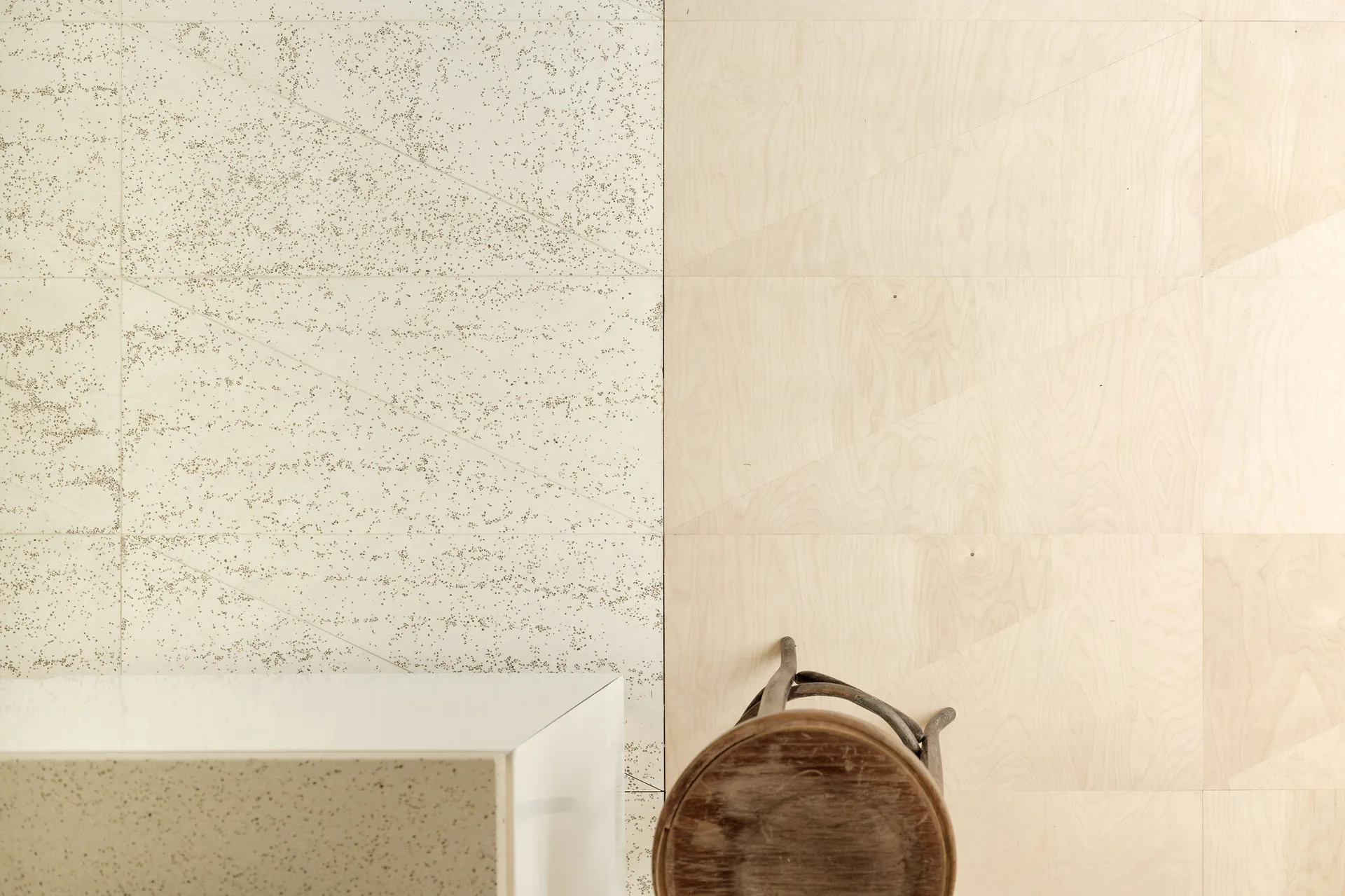 A split wall features speckled beige paneling on the left and light wood veneer panels with thin geometric lines on the right.
