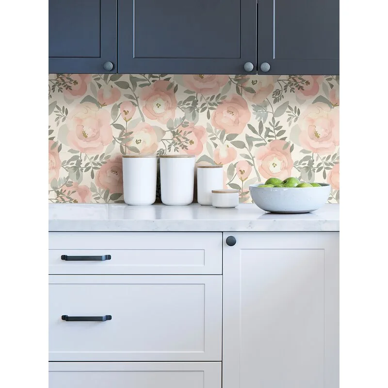 A kitchen counter features a pink floral wallpaper backsplash between dark navy upper cabinets and white lower drawers with black pulls.