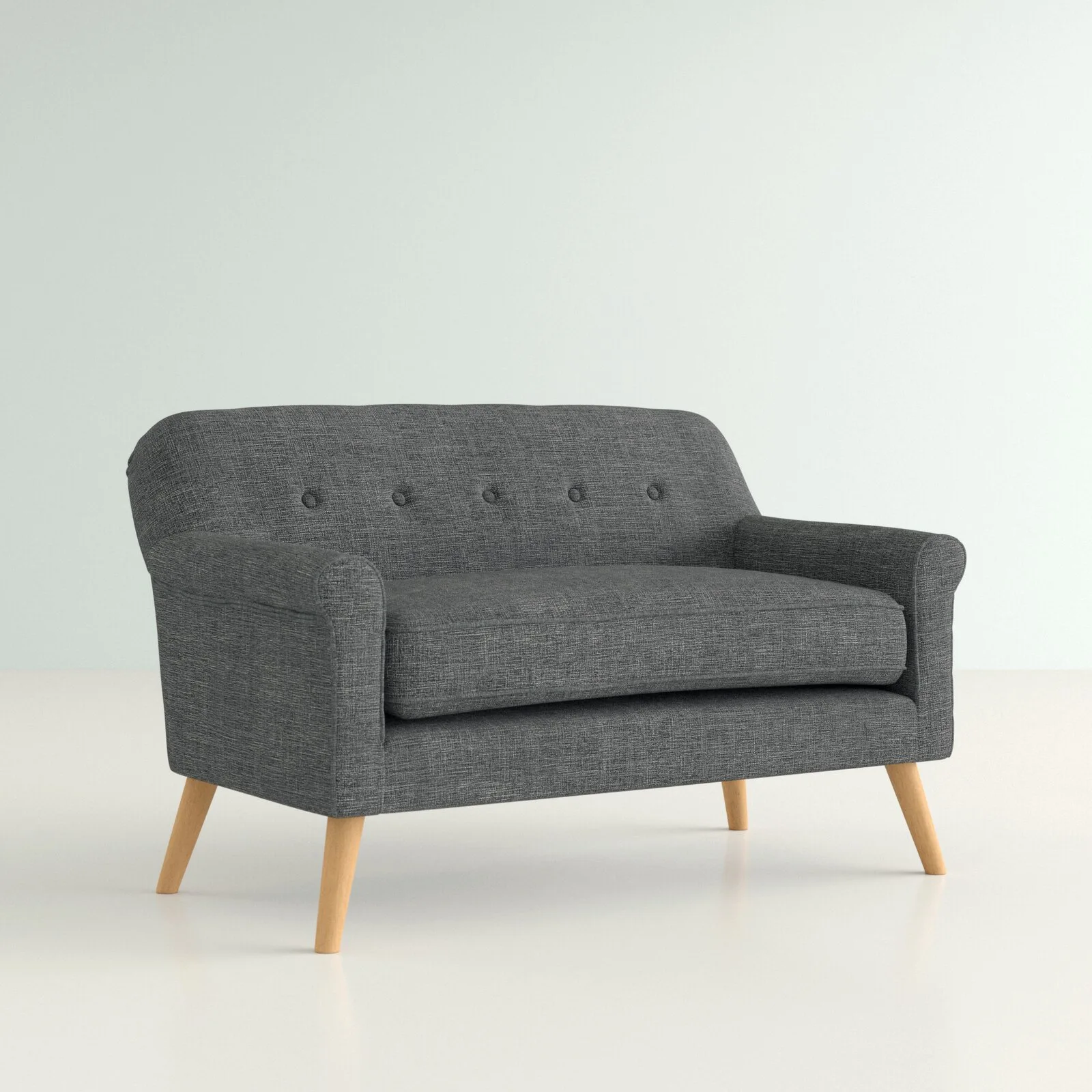 A dark gray upholstered loveseat features button tufting on the backrest and tapered light wood legs against a neutral background.