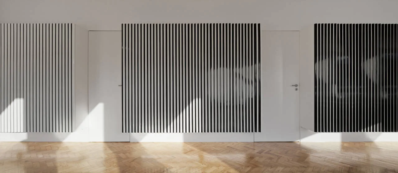 A minimalist white hallway features graphic black and white slatted wall panels, flush interior doors, and a light wood herringbone parquet floor.