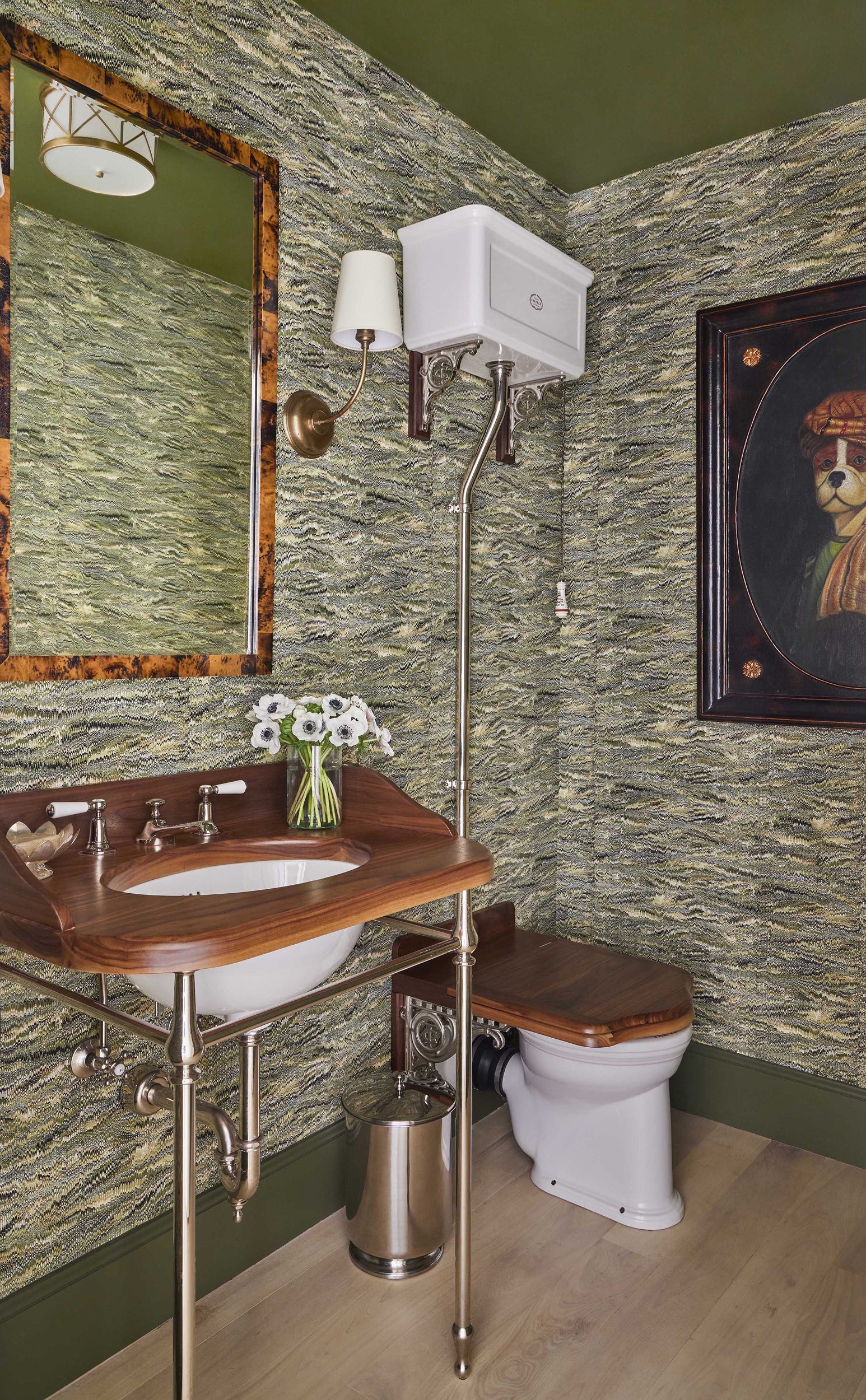 A traditional powder room features green marbled wallpaper, a walnut wood console sink, and a high-tank toilet.