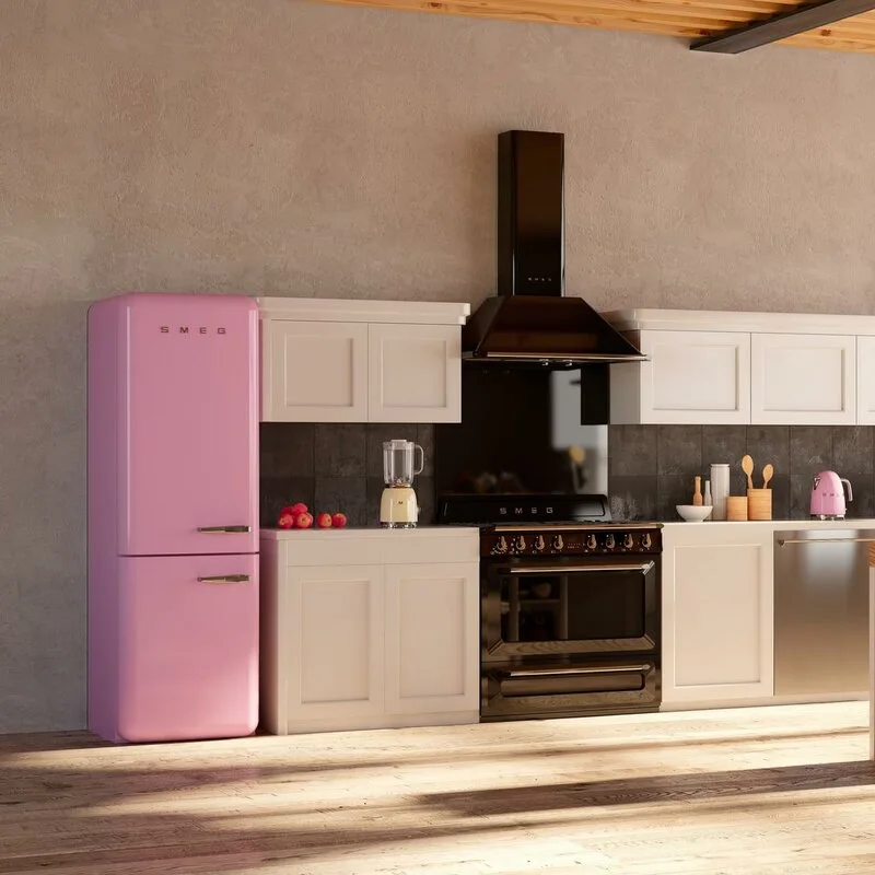 A kitchen featuring a pink retro refrigerator, white shaker-style cabinets, a black range hood, and light-toned wood flooring in natural light.