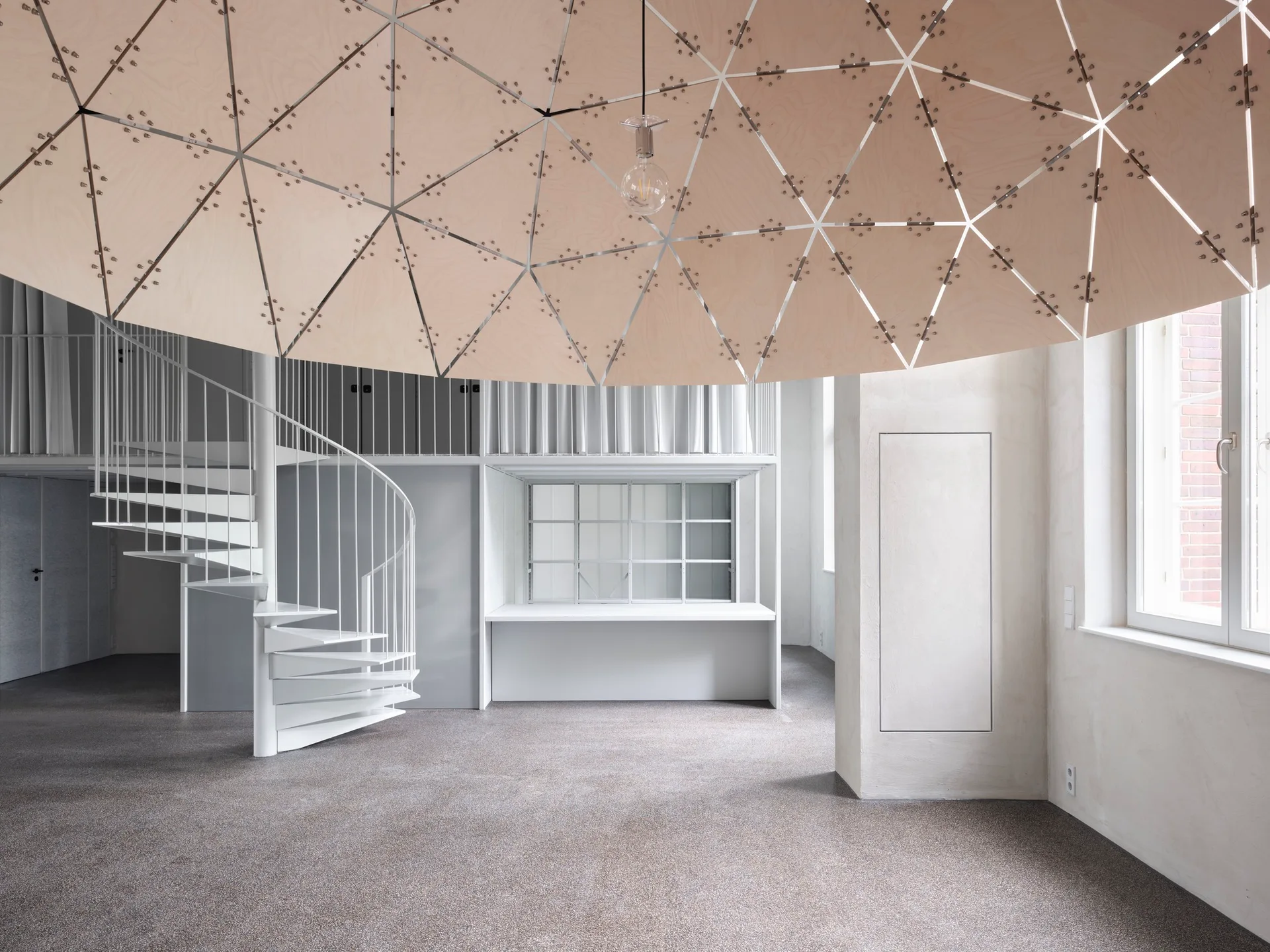 A minimalist interior featuring a white spiral staircase leading to a mezzanine, beneath a large dome-shaped geometric wood canopy.