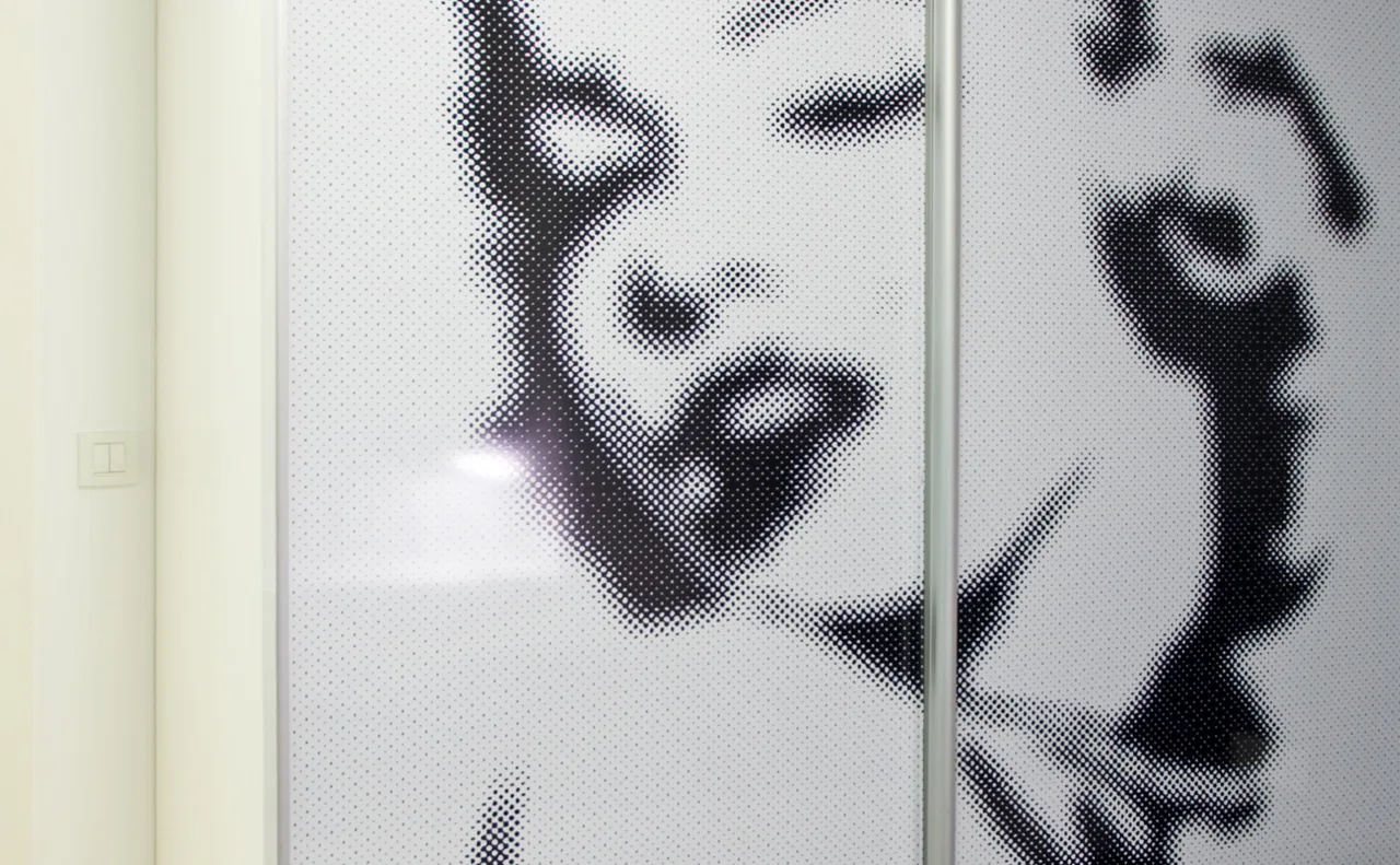 Glossy sliding closet doors featuring a large black and white halftone graphic portrait next to a plain white wall.