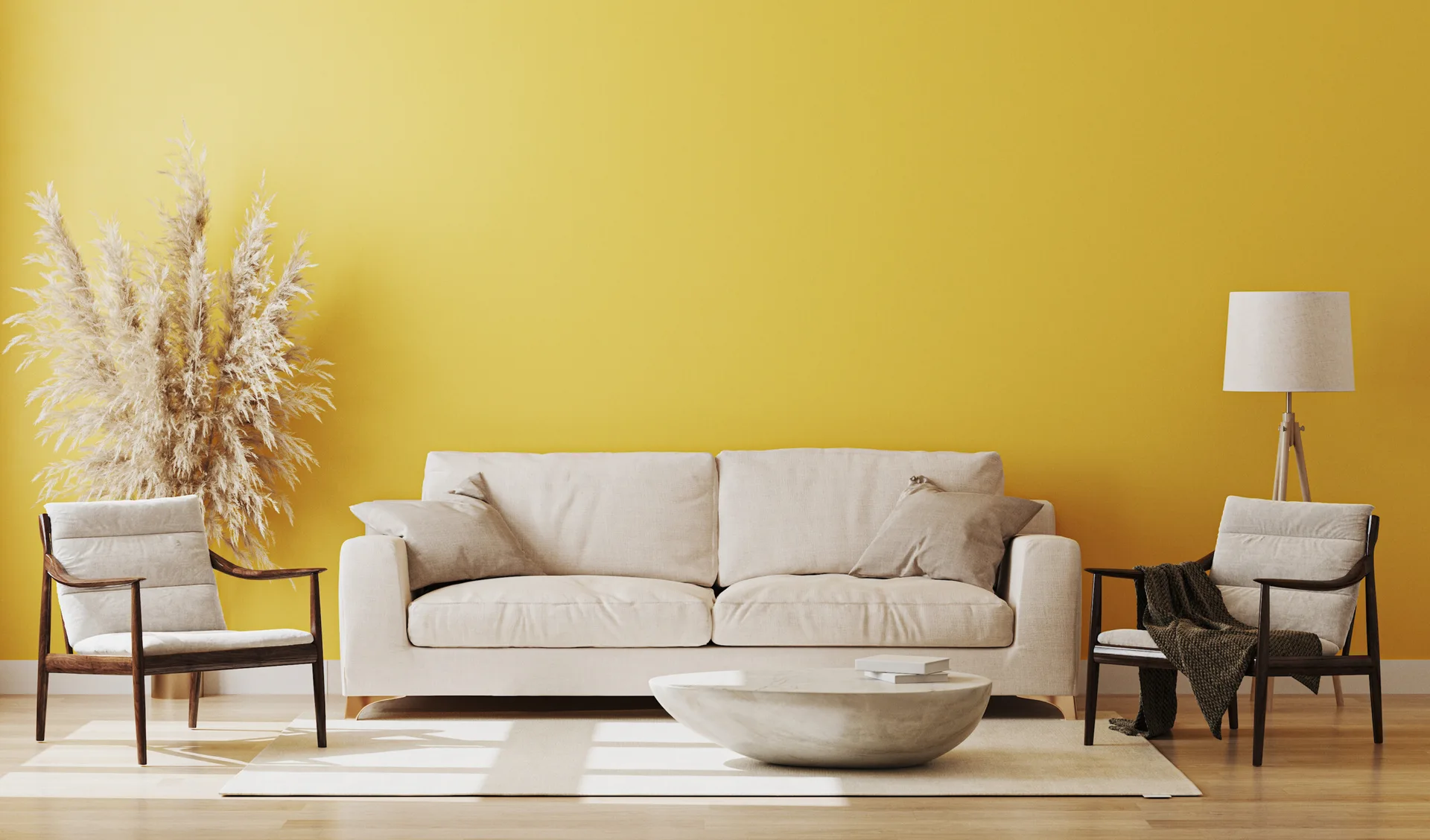 A light beige sofa and two dark wood armchairs are arranged against a bright yellow wall on a light wood floor with a stone coffee table.