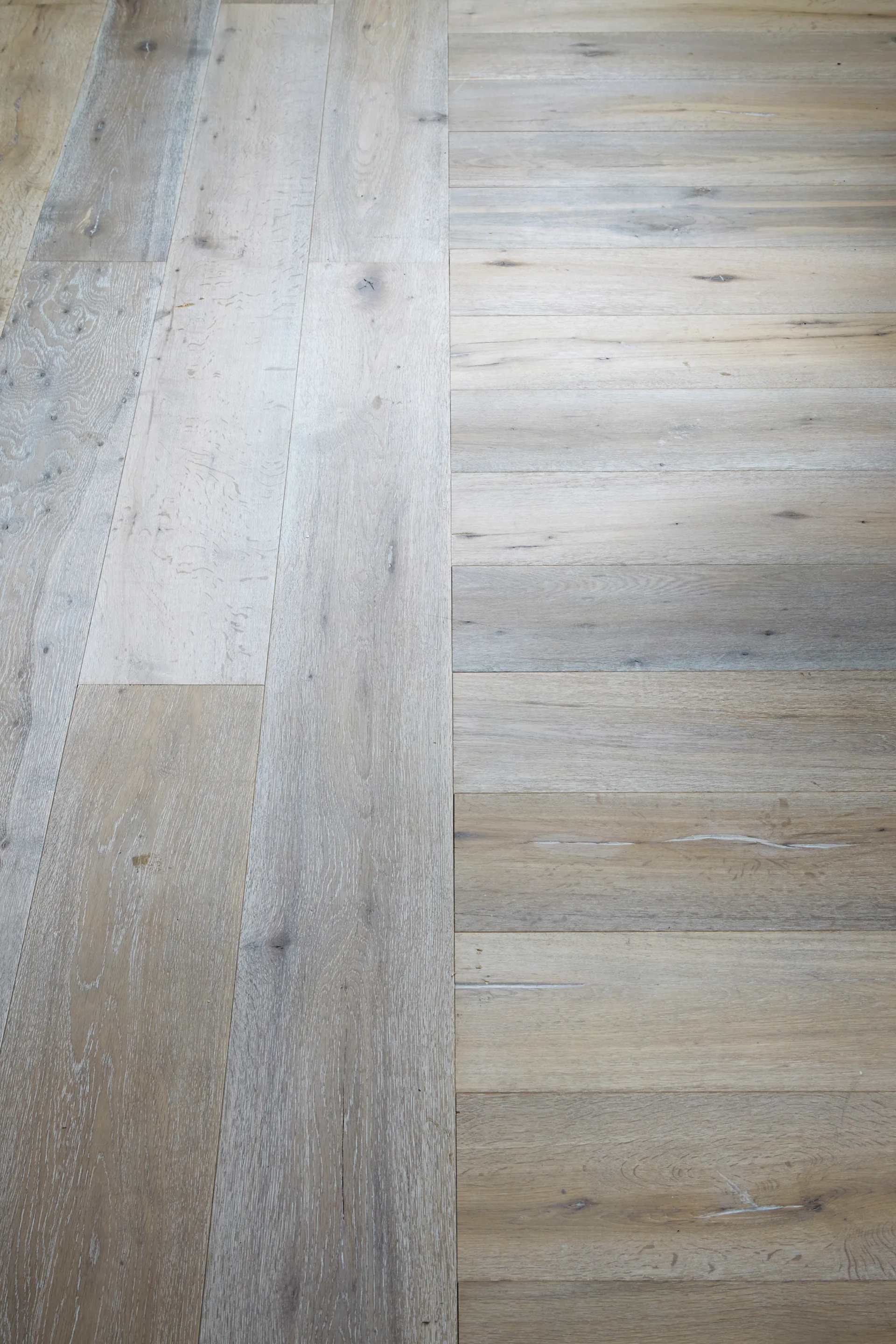 Close-up view of light-colored oak hardwood floor planks laid in a perpendicular pattern with visible wood grain and a matte finish.