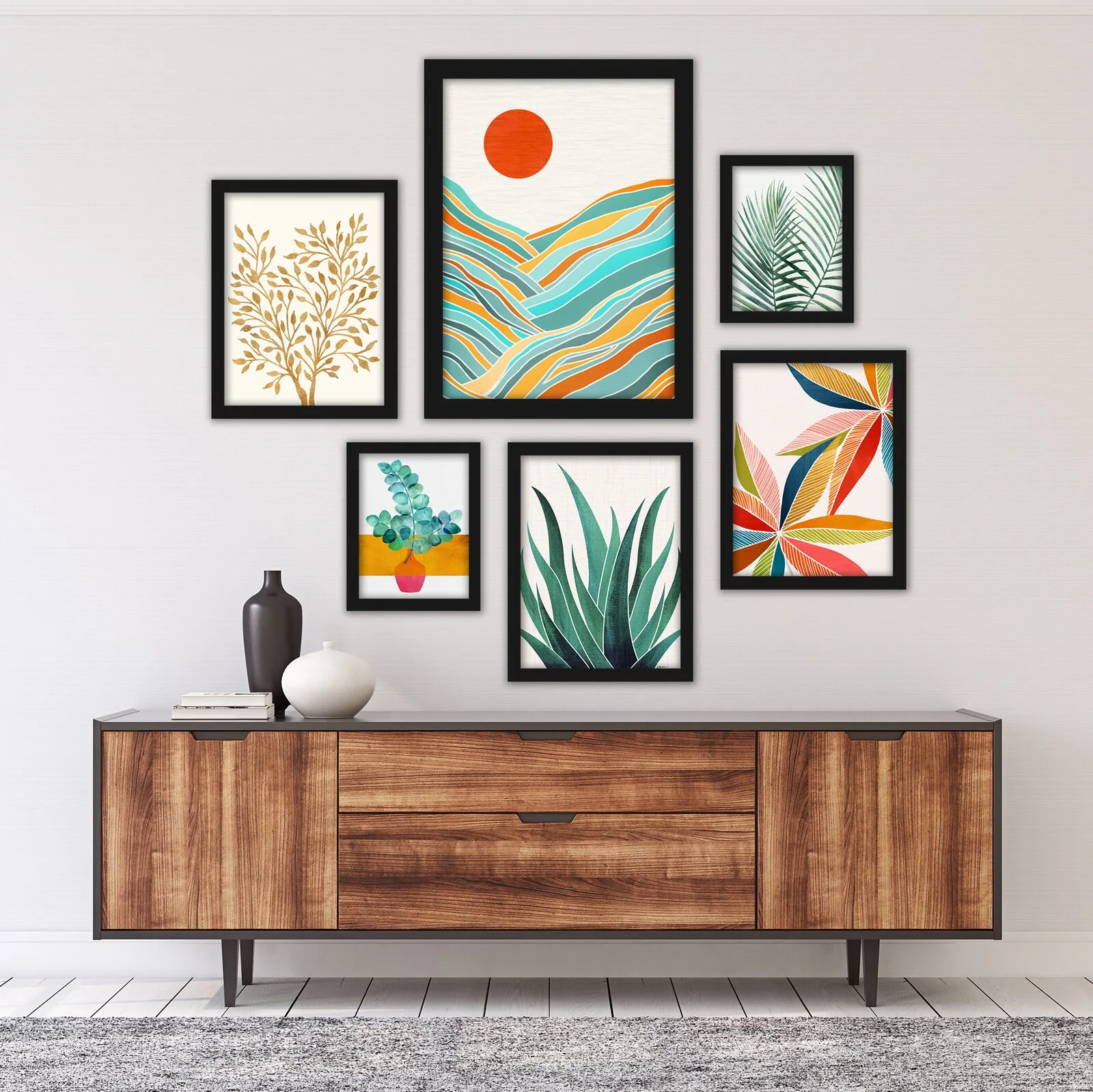 A wooden sideboard with decorative vases sits beneath a gallery wall of six colorful botanical art prints in black frames against a white wall.
