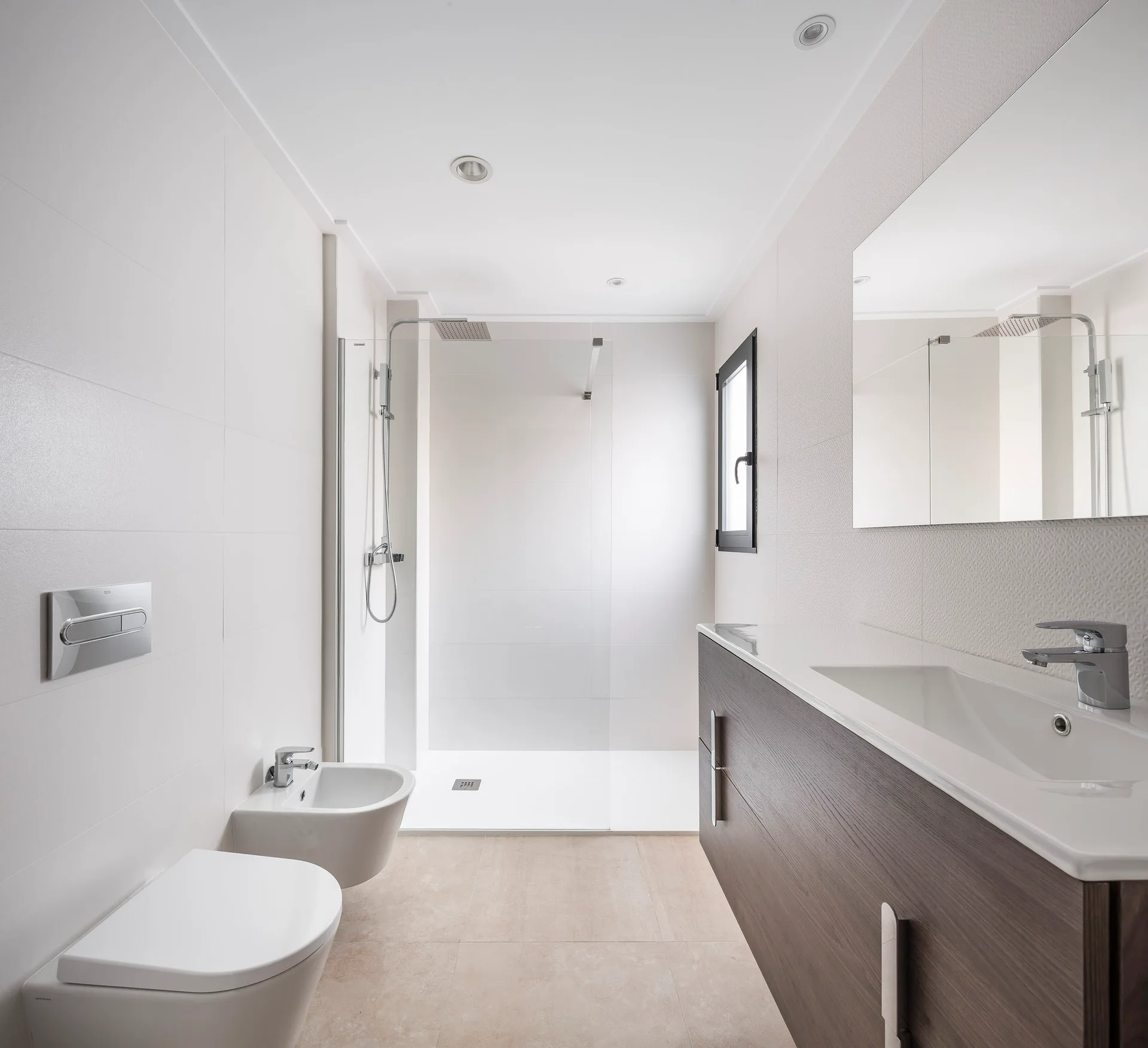 A modern bathroom with a floating dark wood vanity, white wall-hung toilet and bidet, and a glass-enclosed walk-in shower.