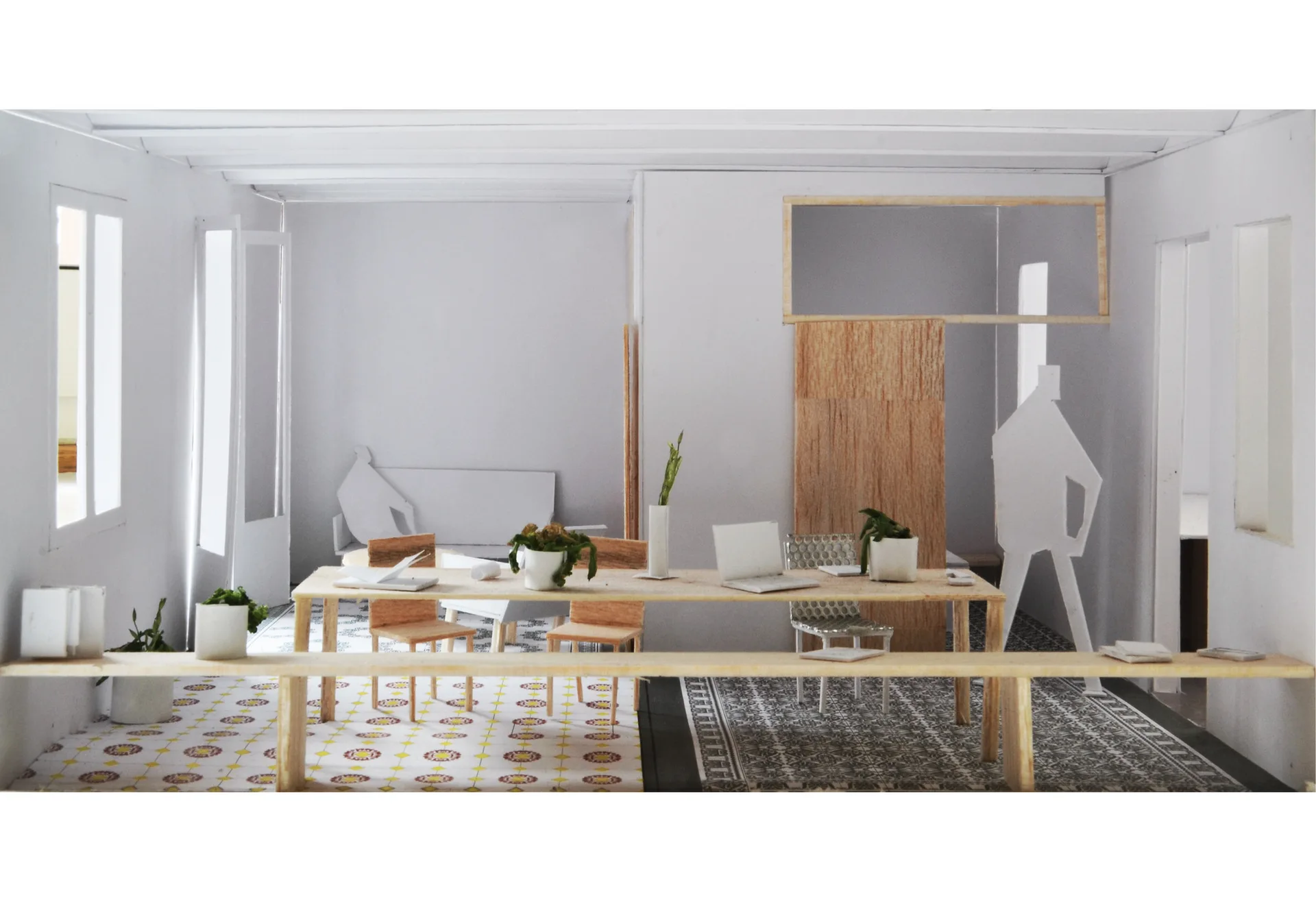 An architectural scale model of an interior space featuring a long wood dining table, patterned geometric tiles, and minimalist scale figures.