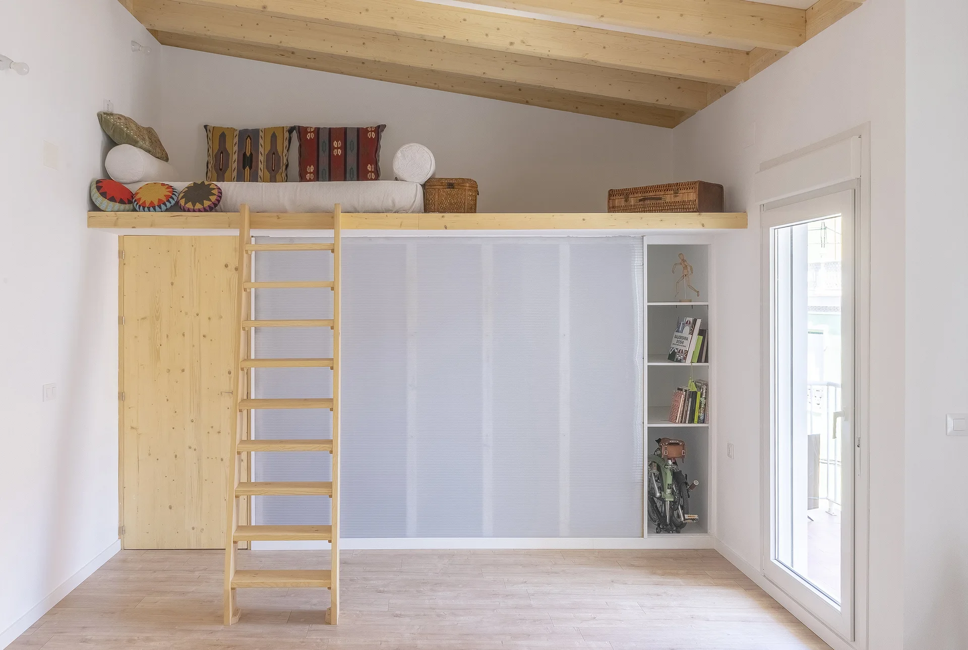 A minimalist white bedroom features a natural wood loft bed platform with a ladder, translucent sliding storage panels, and sloped beamed ceilings.
