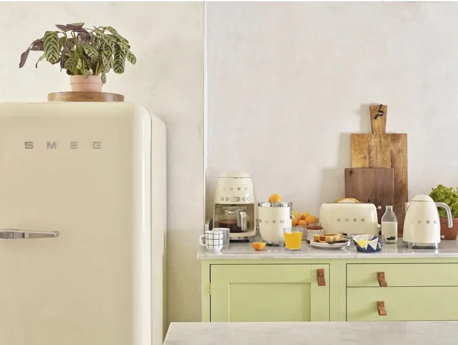 Cream retro appliances and a refrigerator sit on a pale green cabinet with a stone countertop.