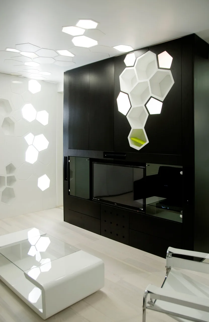 A modern living room featuring a matte black media unit with integrated hexagonal lighting that extends to the ceiling and walls.