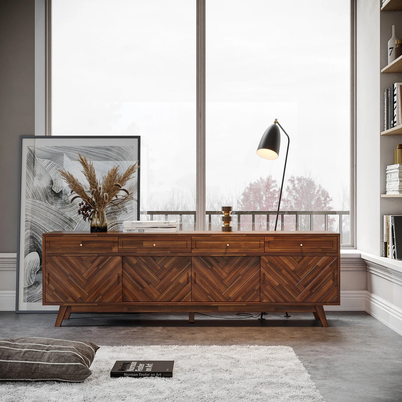 A mid-century wooden sideboard with chevron-patterned doors sits on a concrete floor in front of a large window next to framed artwork.